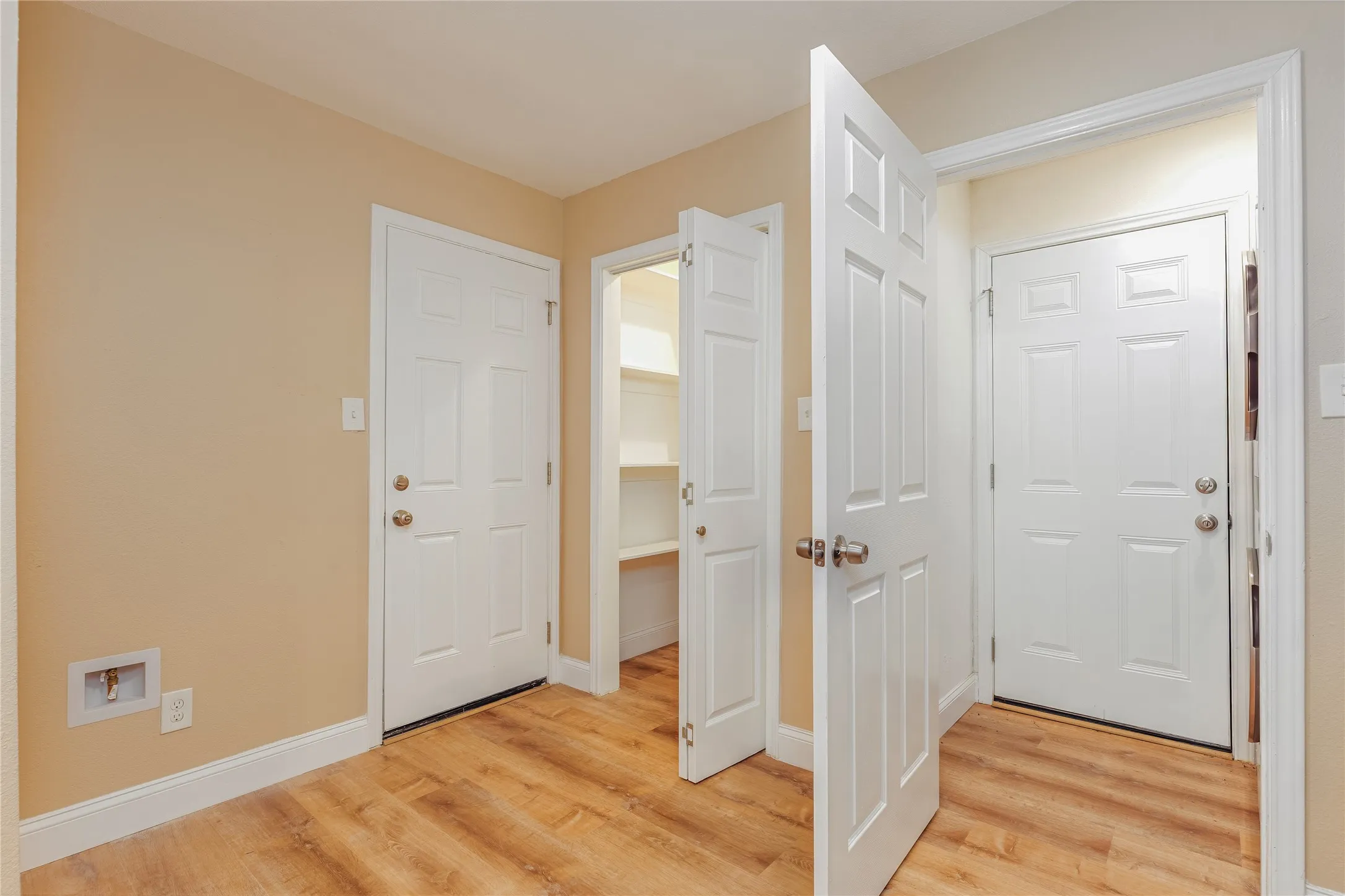 LVP flooring, light-toned wall paint, multiple paneled doors, and built-in shelving