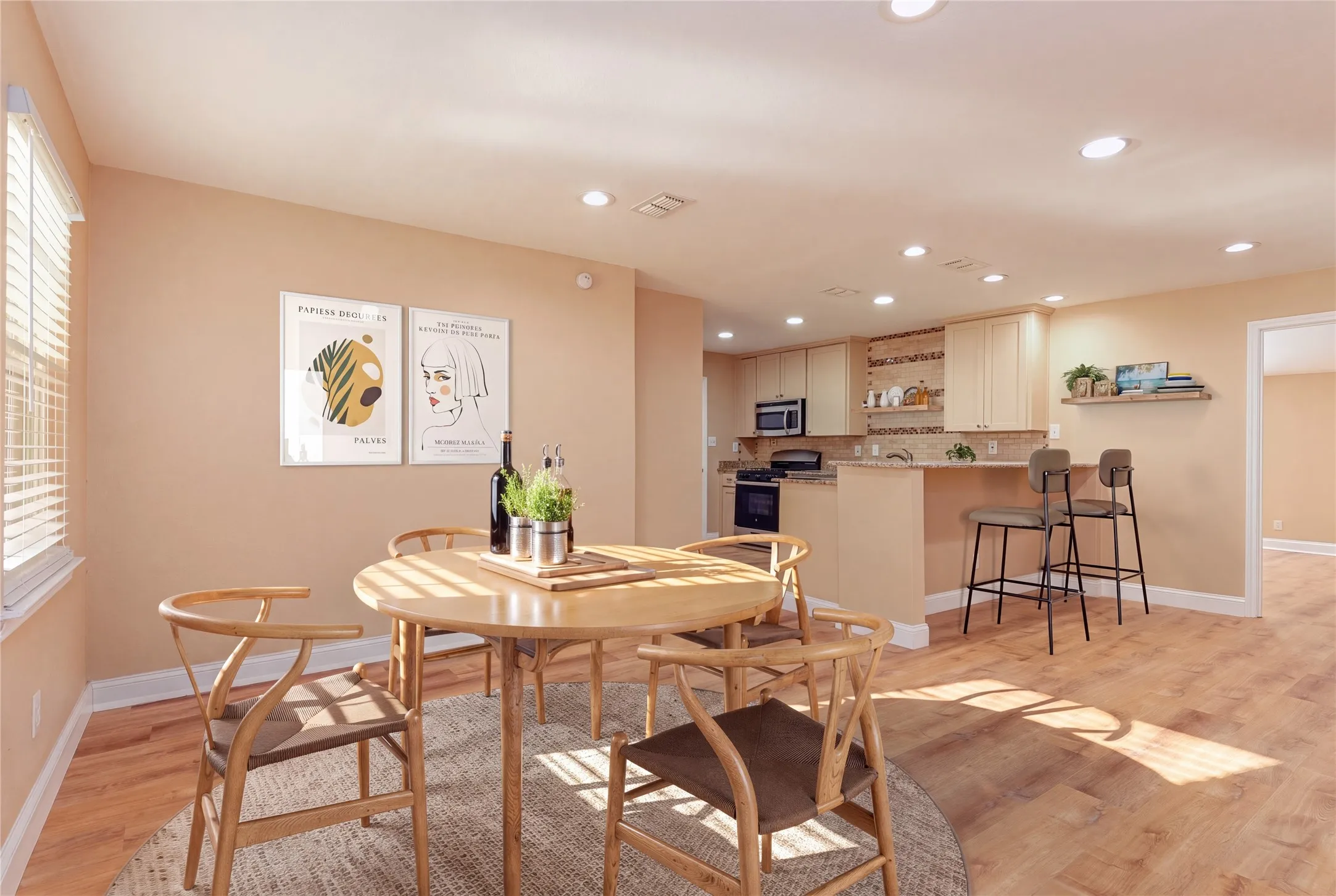 Light LVP flooring throughout, recessed lighting, kitchen with light-colored cabinetry, built-in microwave, and breakfast bar