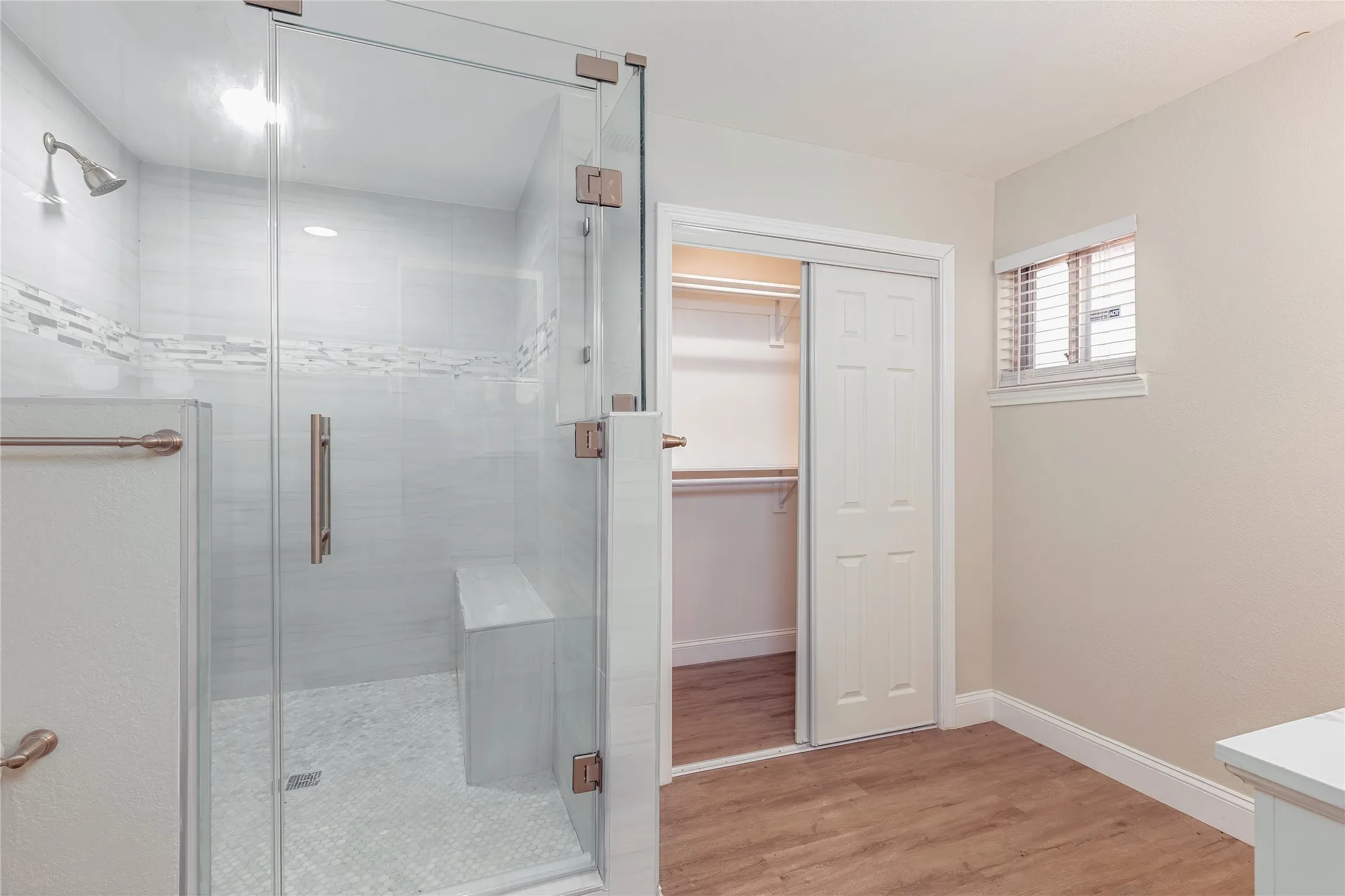 Glass-enclosed shower with a built-in bench, tiled walls, and a decorative tile band