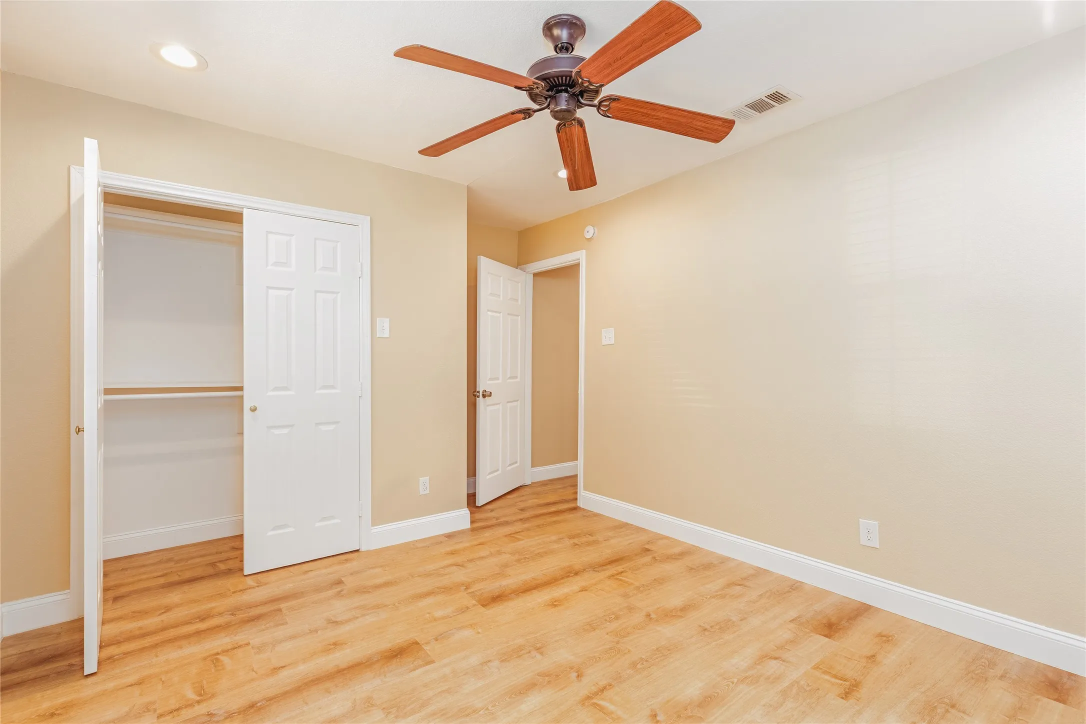 LVP flooring, recessed lighting, ceiling fan with wood-tone blades, and a built-in closet with dual doors