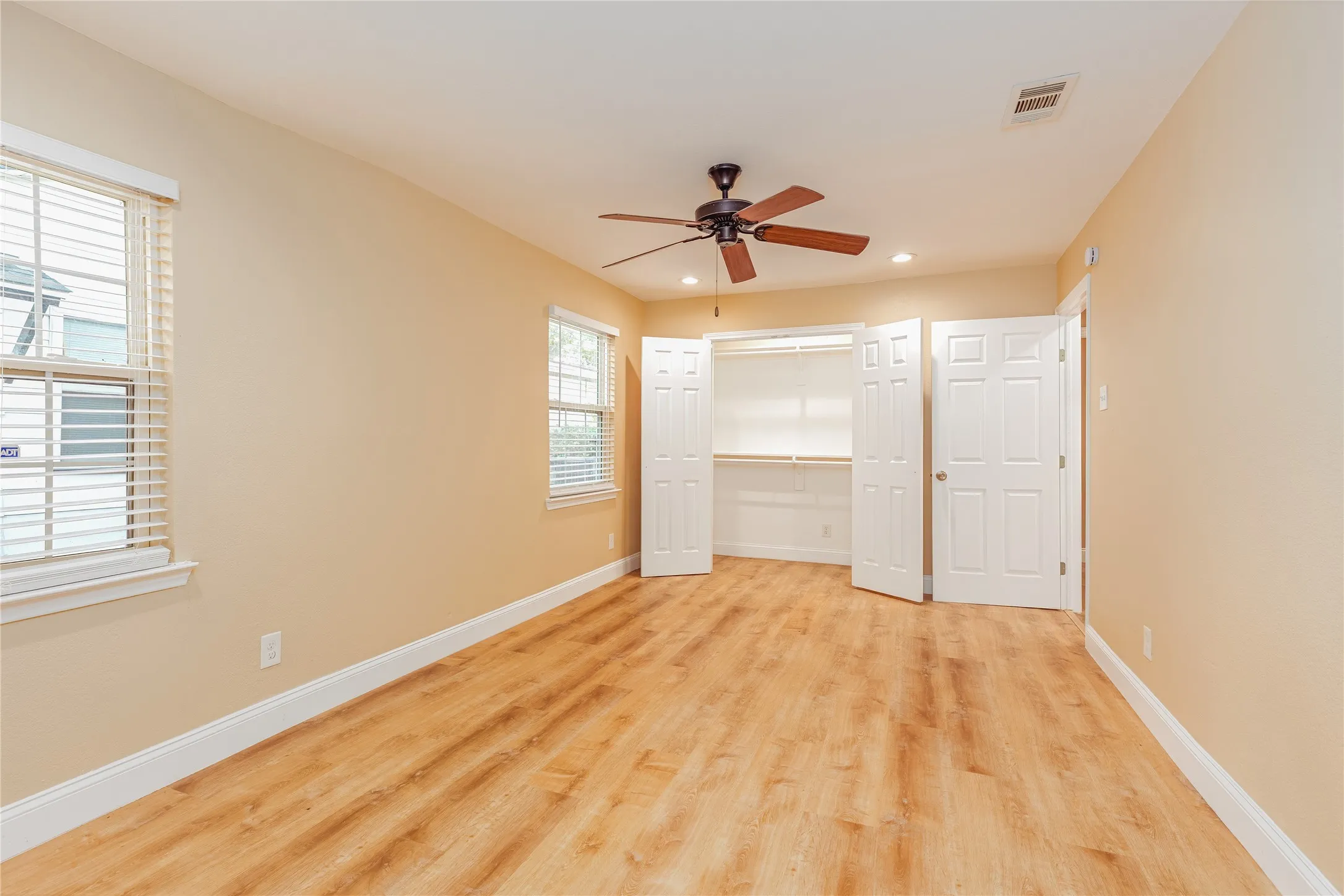 LVP flooring, ceiling fan, recessed lighting, double windows with blinds, and built-in closet shelving