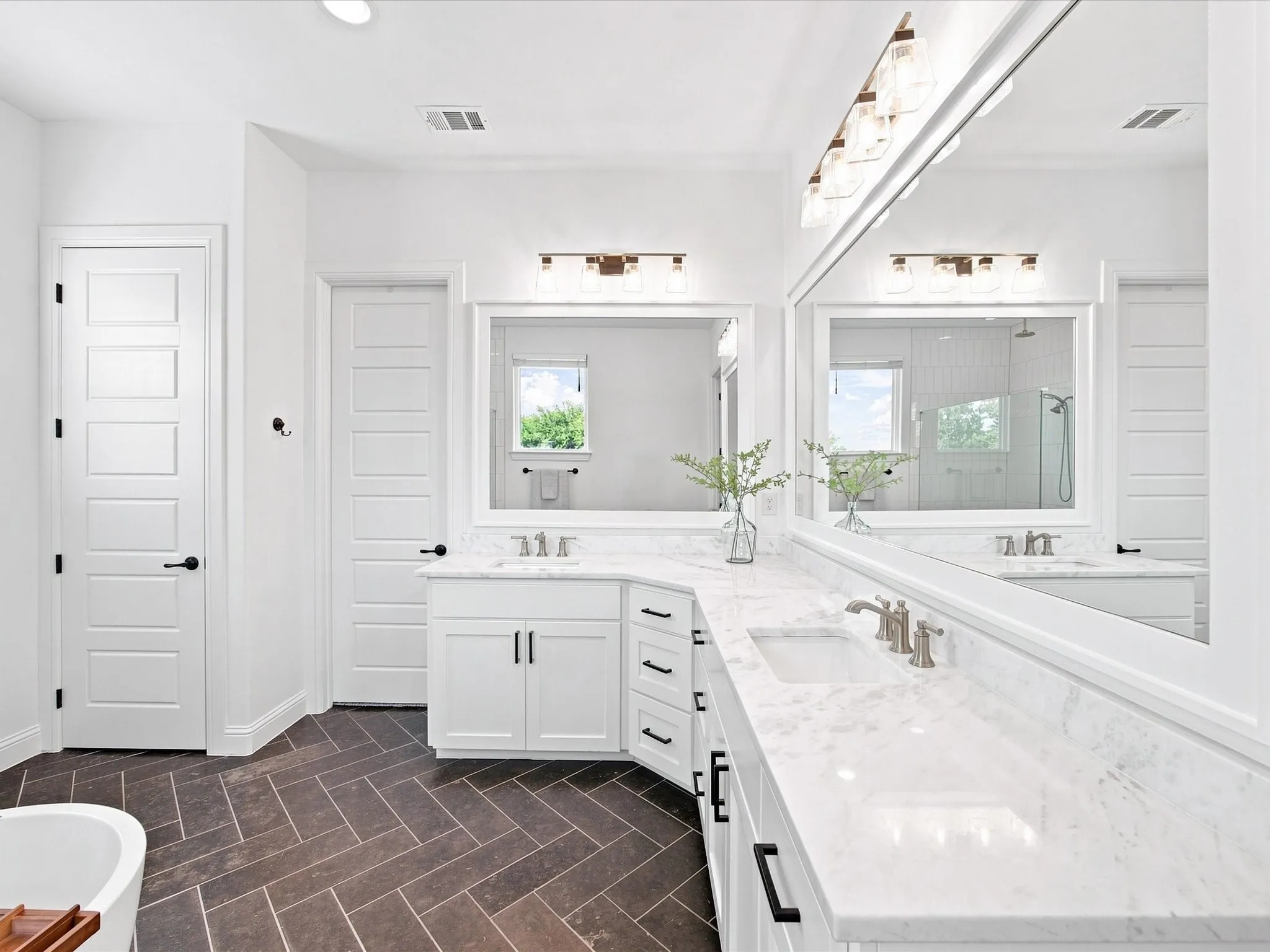 Dual vanities with white cabinetry, integrated sinks, and light-toned countertops