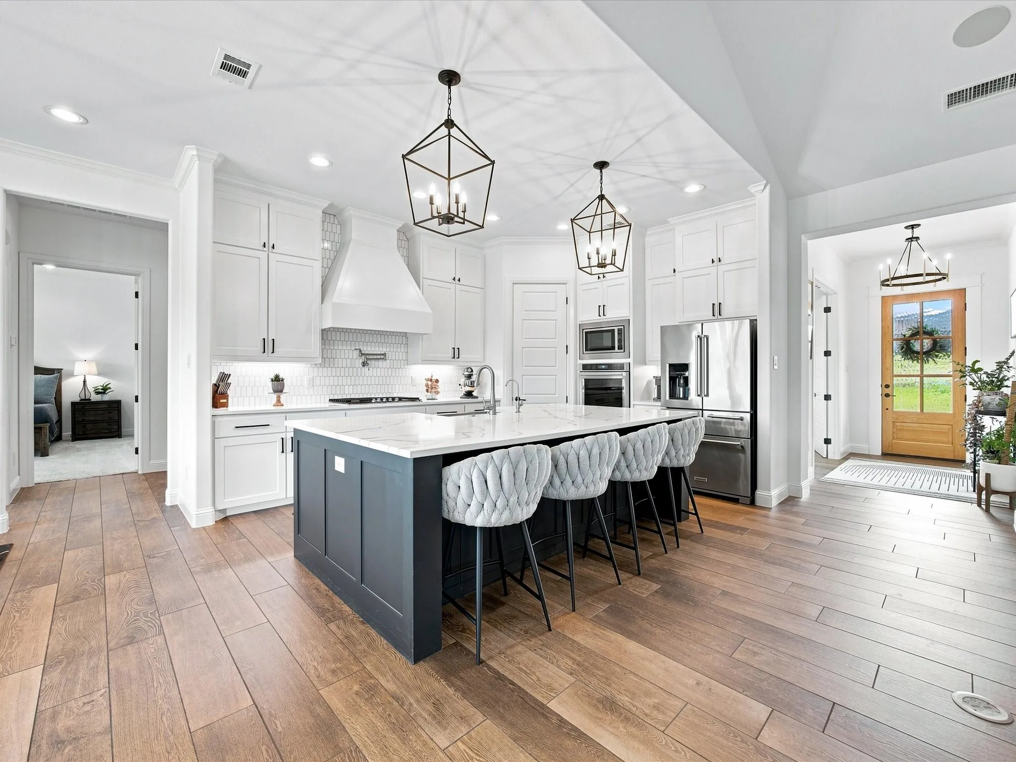 Gourmet kitchen featuring a large island with seating, stainless steel appliances, a range hood, and wood-finish flooring