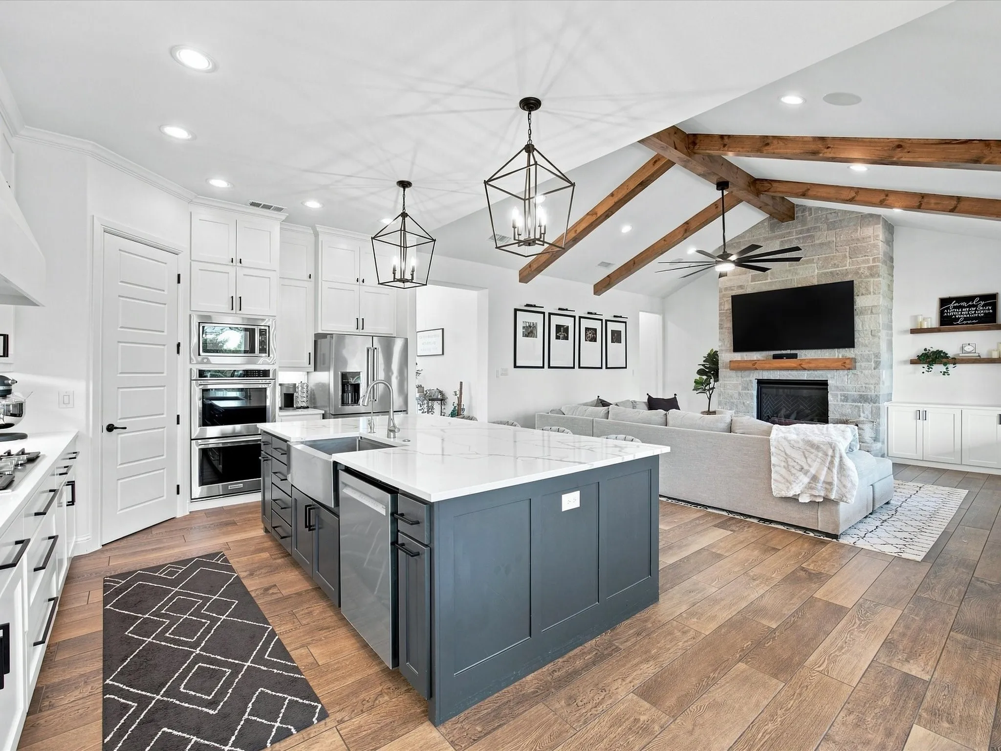 Open-concept living area with vaulted ceilings, exposed wood beams, and wood-finish flooring