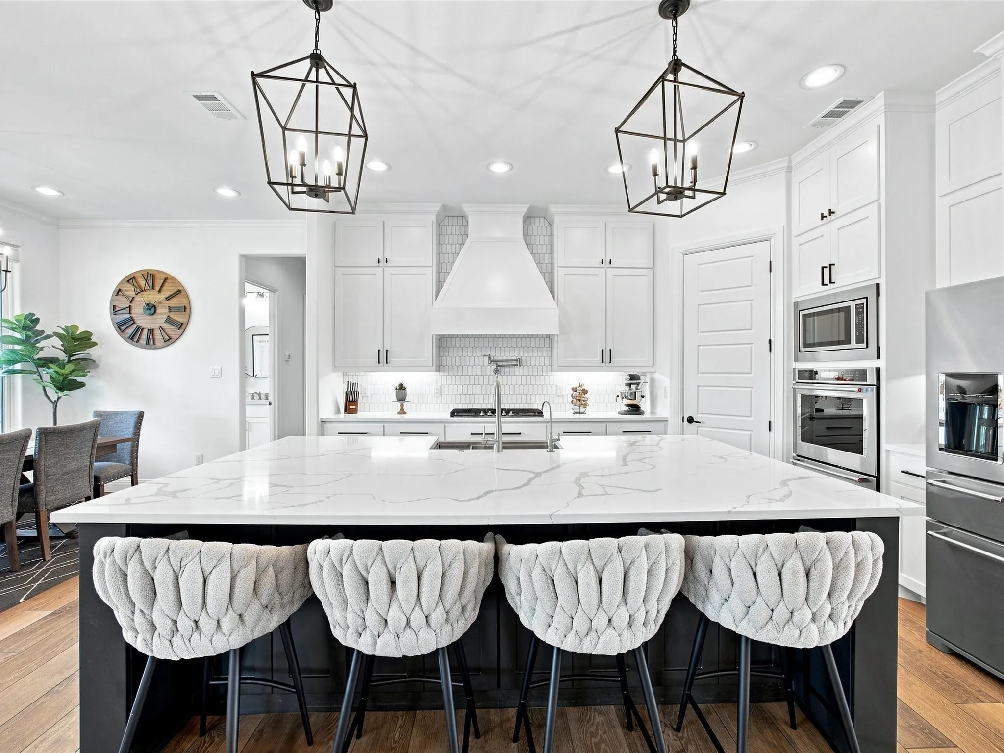 Spacious kitchen featuring a large island with a quartz countertop, white shaker-style cabinetry, and integrated stainless steel appliances