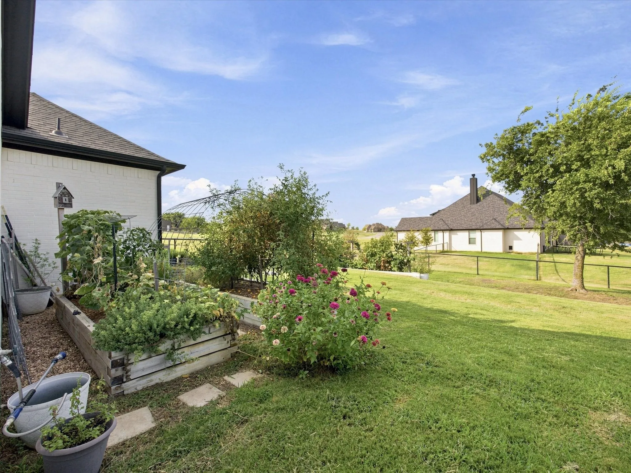 Expansive backyard featuring a manicured lawn, established garden beds, and mature trees