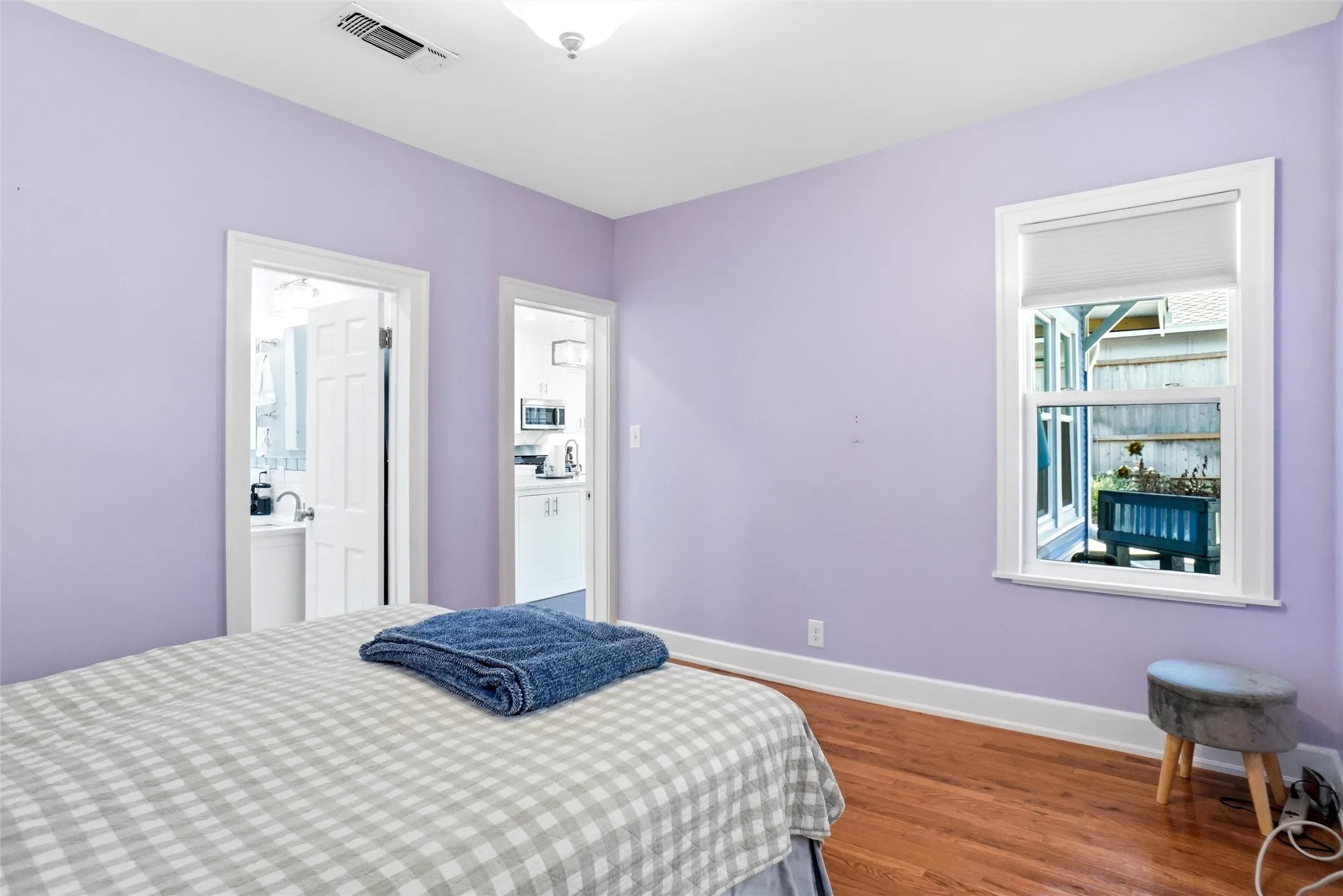 Room featuring a window with privacy blind, wood-finish flooring, and white baseboards