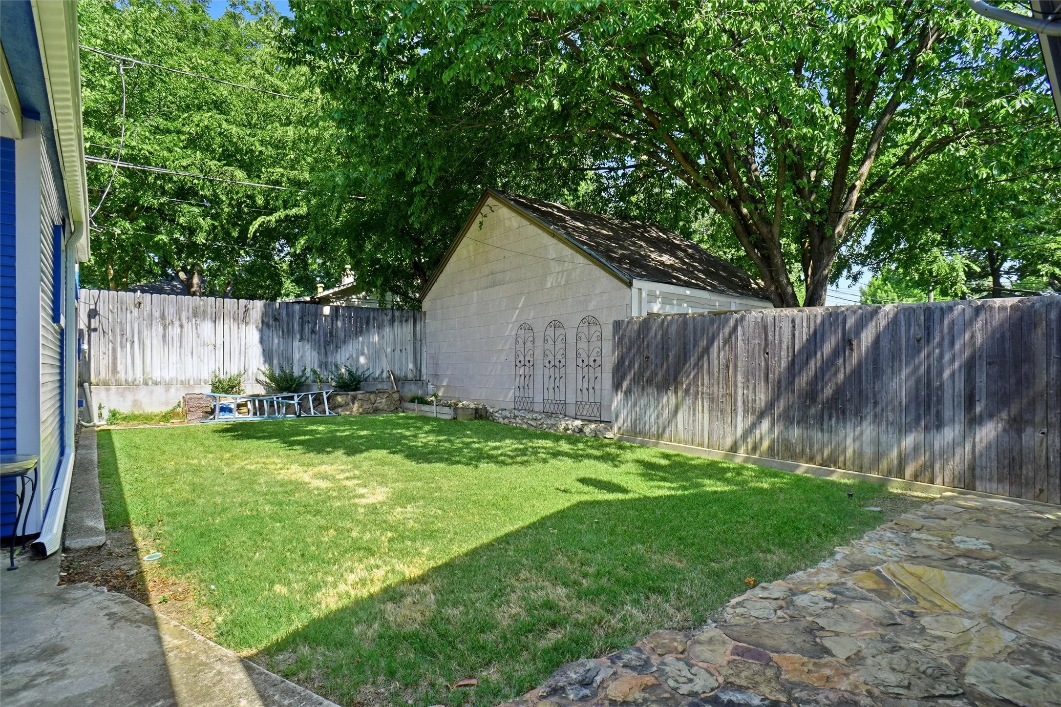 Private backyard space featuring a manicured lawn, flagstone patio, and mature perimeter trees