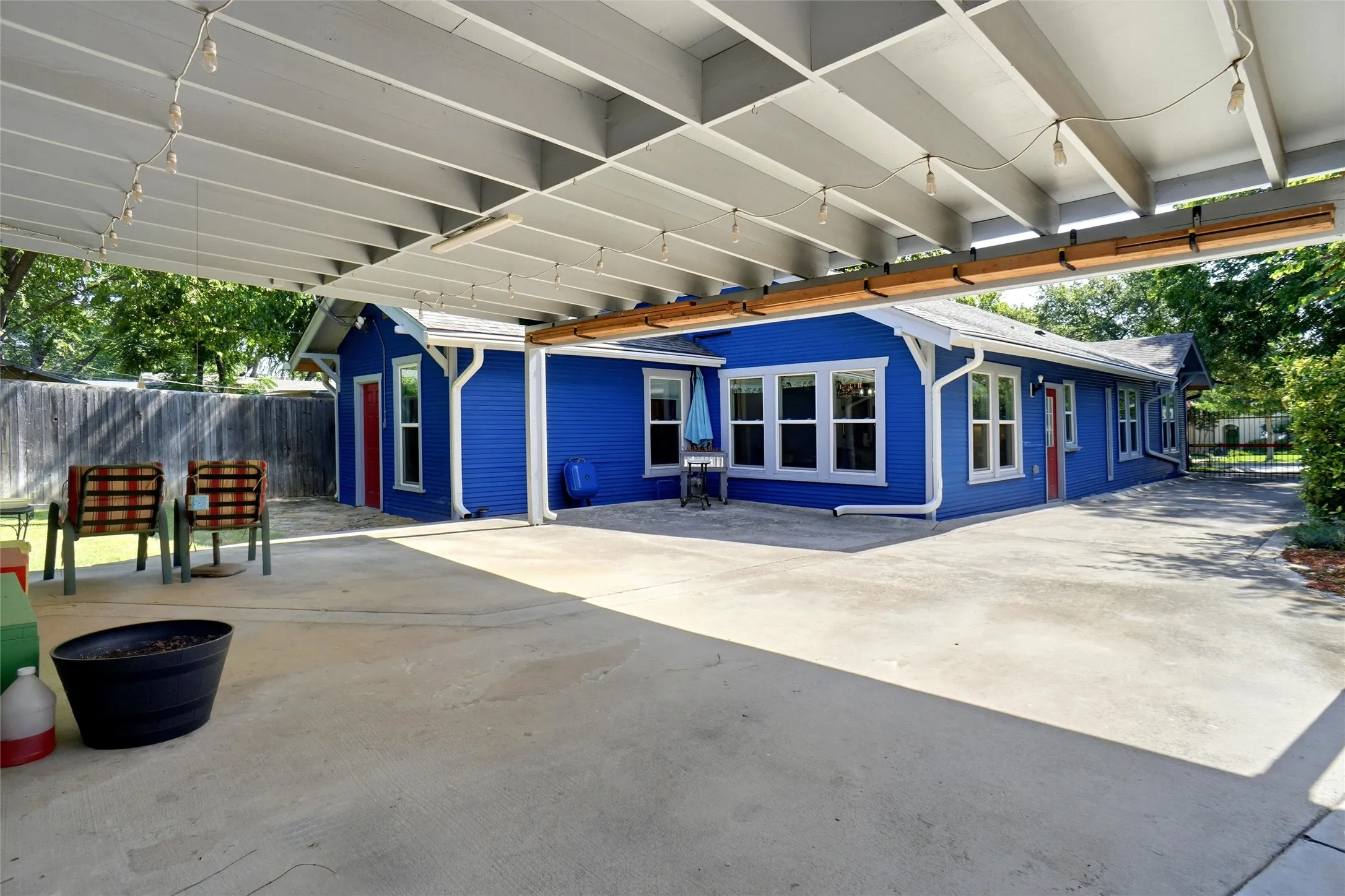 Expansive concrete patio with a slatted overhead cover