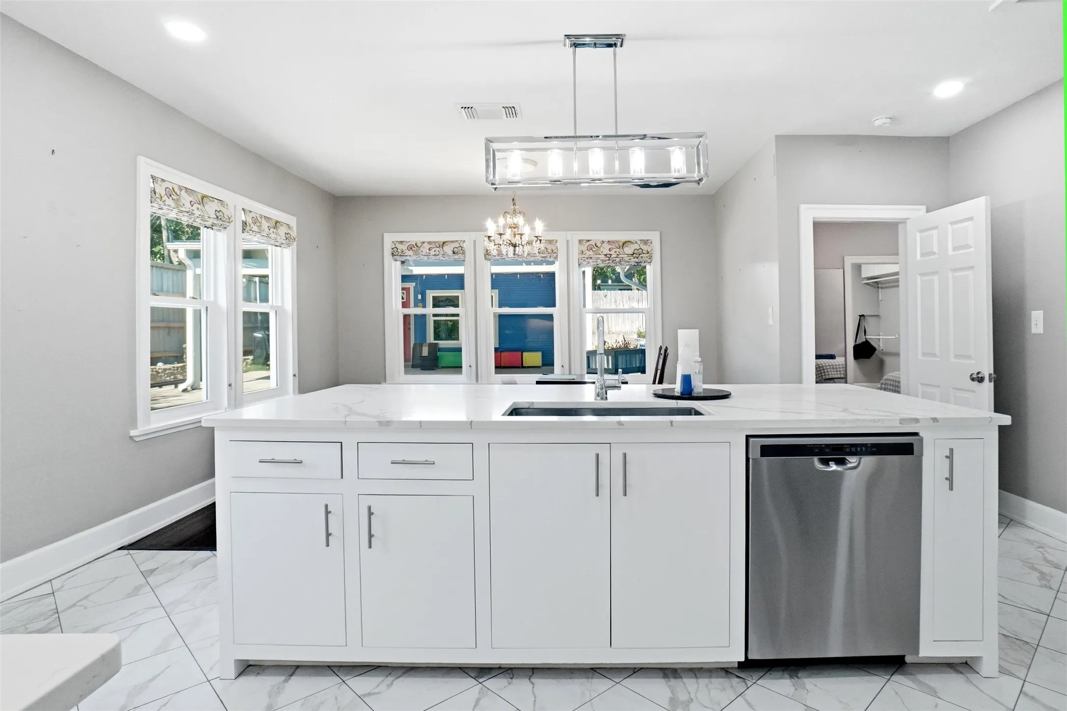 Central kitchen island featuring a white countertop, undermount sink, and stainless steel dishwasher