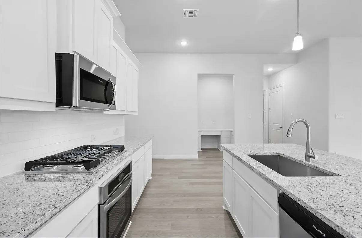 Open-concept kitchen featuring white shaker cabinetry, stainless steel appliances, speckled stone countertops, and light wood-finish flooring
