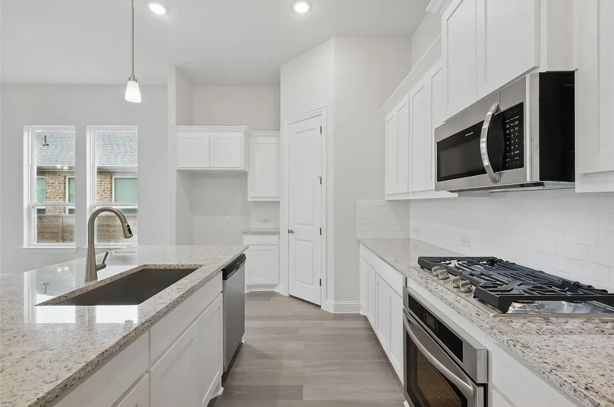 Contemporary kitchen featuring white cabinetry, granite countertops, stainless steel appliances, wood-finish flooring, and a subway tile backsplash