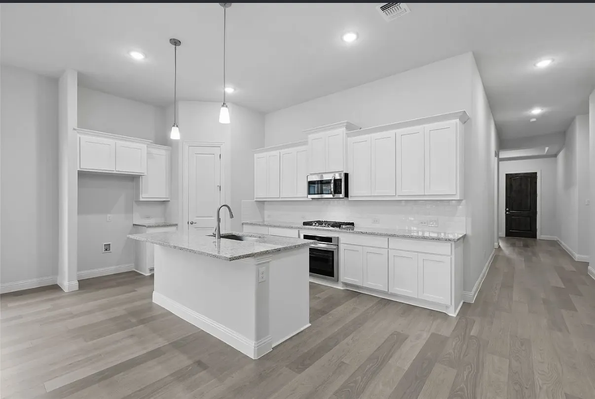 Contemporary kitchen featuring white cabinetry, light-toned wood-finish flooring, a central island with a sink and pendant lighting, granite countertops, and stainless steel appliances