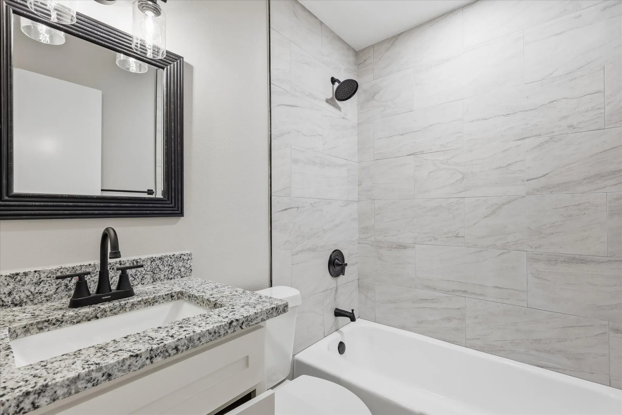 Bathroom featuring a white vanity with granite-style countertop, undermount sink, and matte black faucet