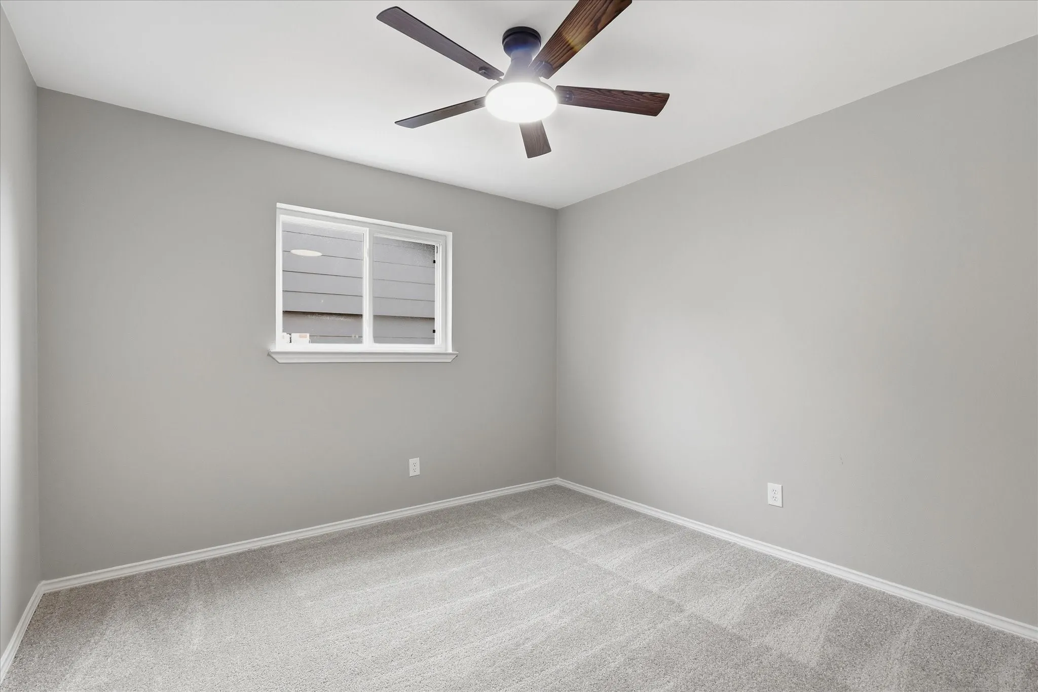 Carpeted room featuring a ceiling fan with integrated lighting, a single window, and light gray wall paint