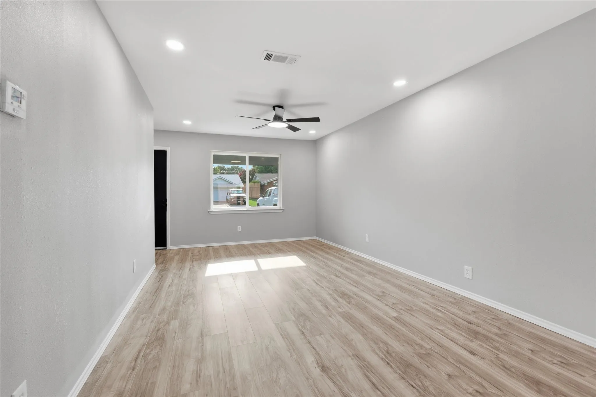 Spacious room featuring wood-finish flooring, recessed lighting, and a ceiling fan