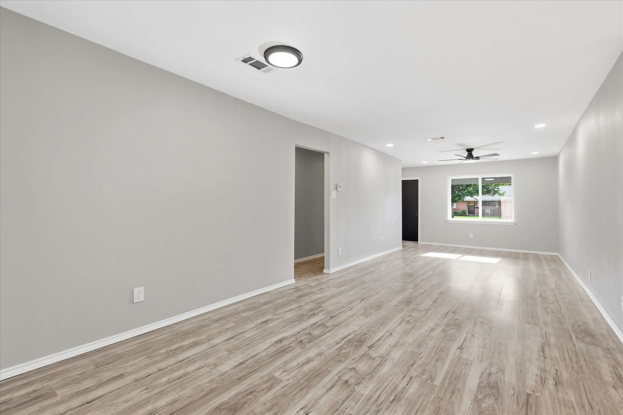 Spacious room featuring wood-finish flooring, light gray walls, and white baseboards