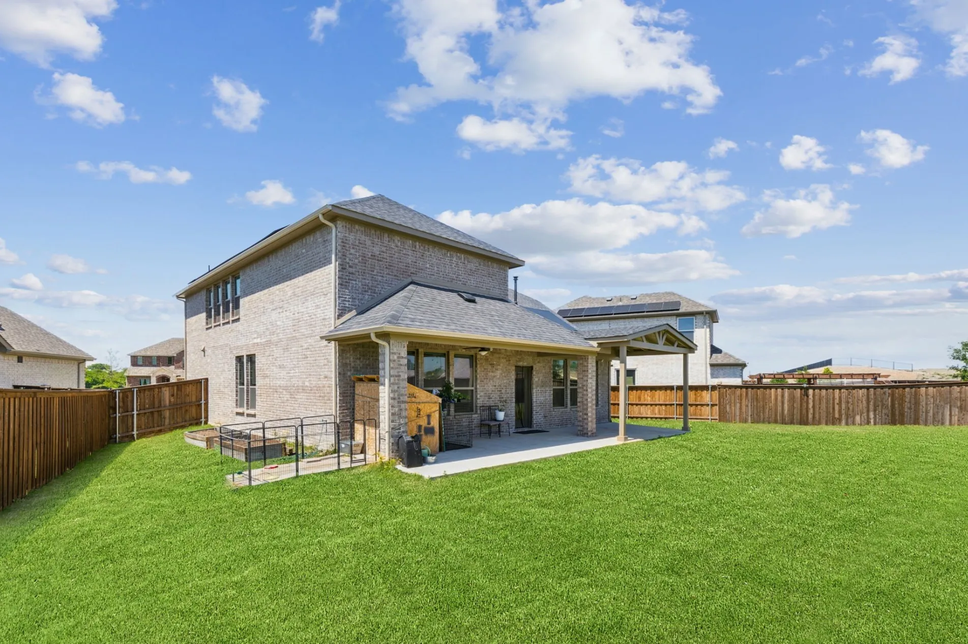 Expansive fenced backyard featuring a substantial covered patio, a separate covered pergola, and a large lawn area