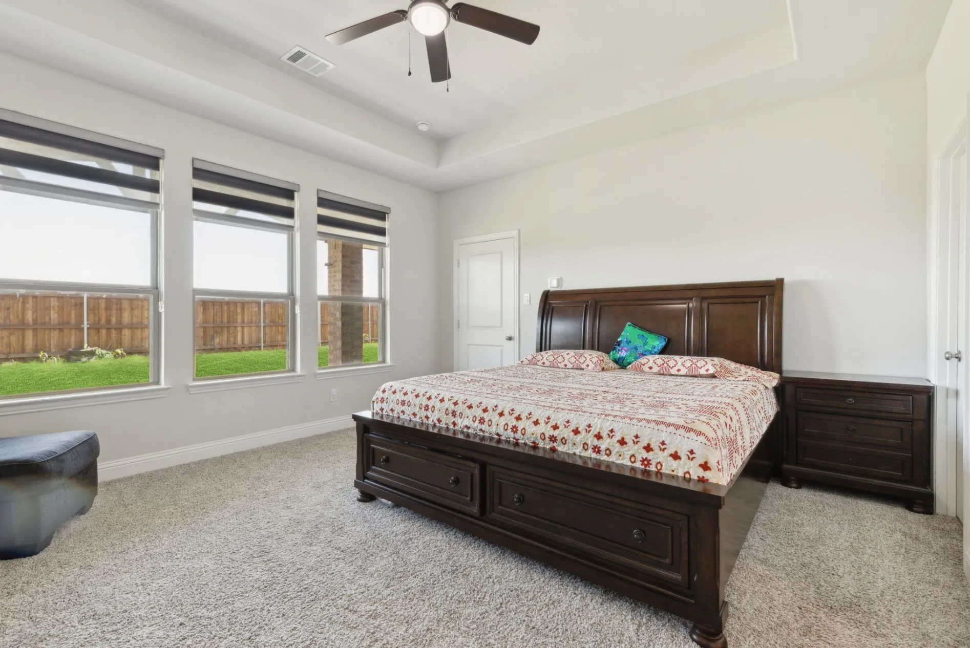 Room featuring multiple windows, tray ceiling, ceiling fan, carpet flooring, and a white paneled door