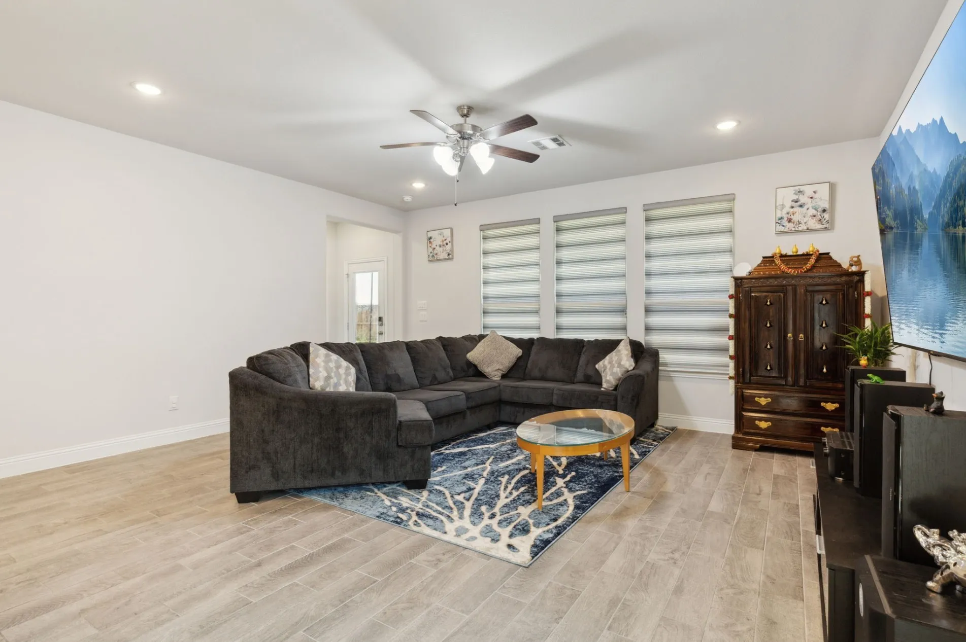 Spacious living area featuring wood-finish tile flooring, recessed lighting, and a ceiling fan