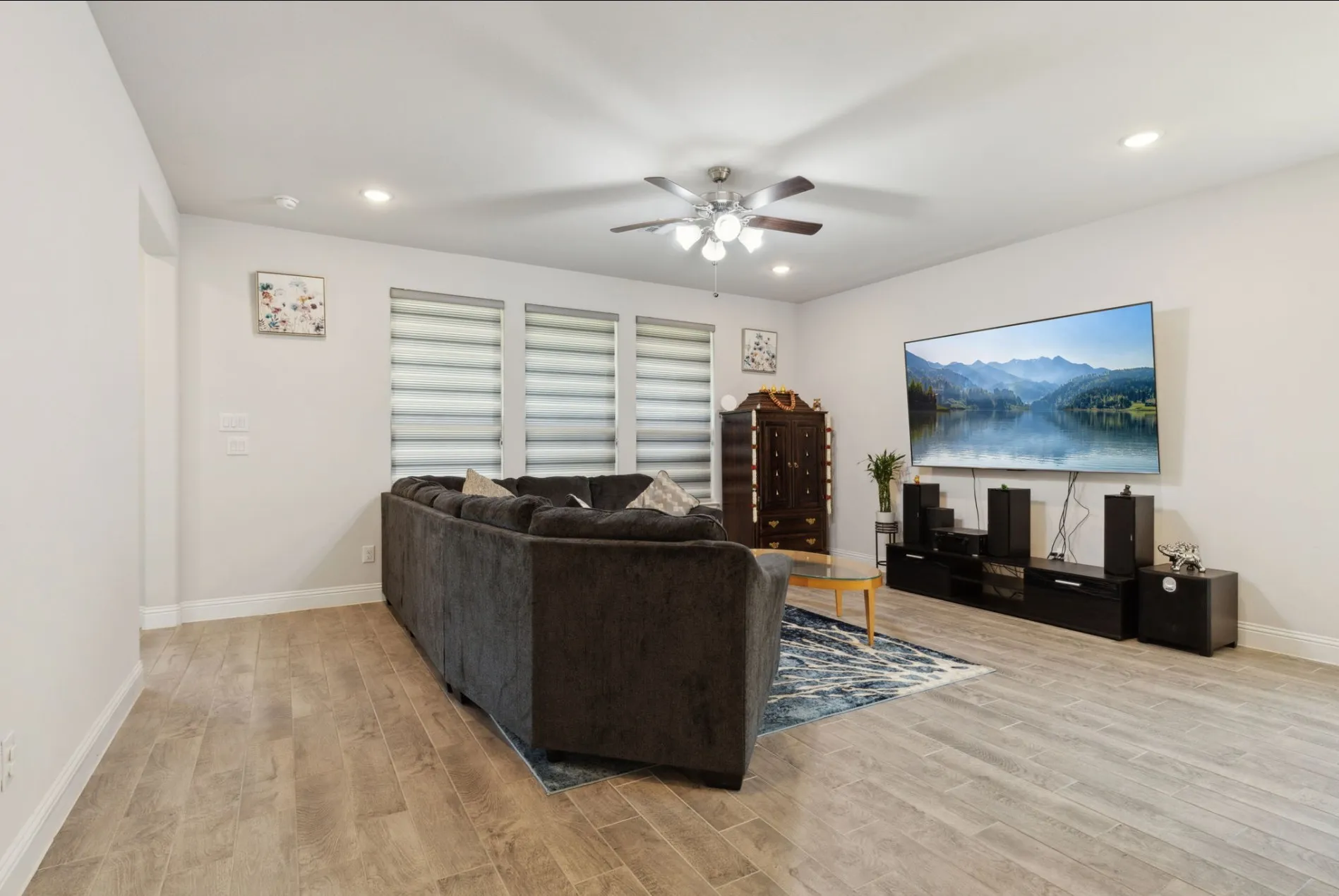 Spacious living area featuring wood-look tile flooring, recessed lighting, and a ceiling fan