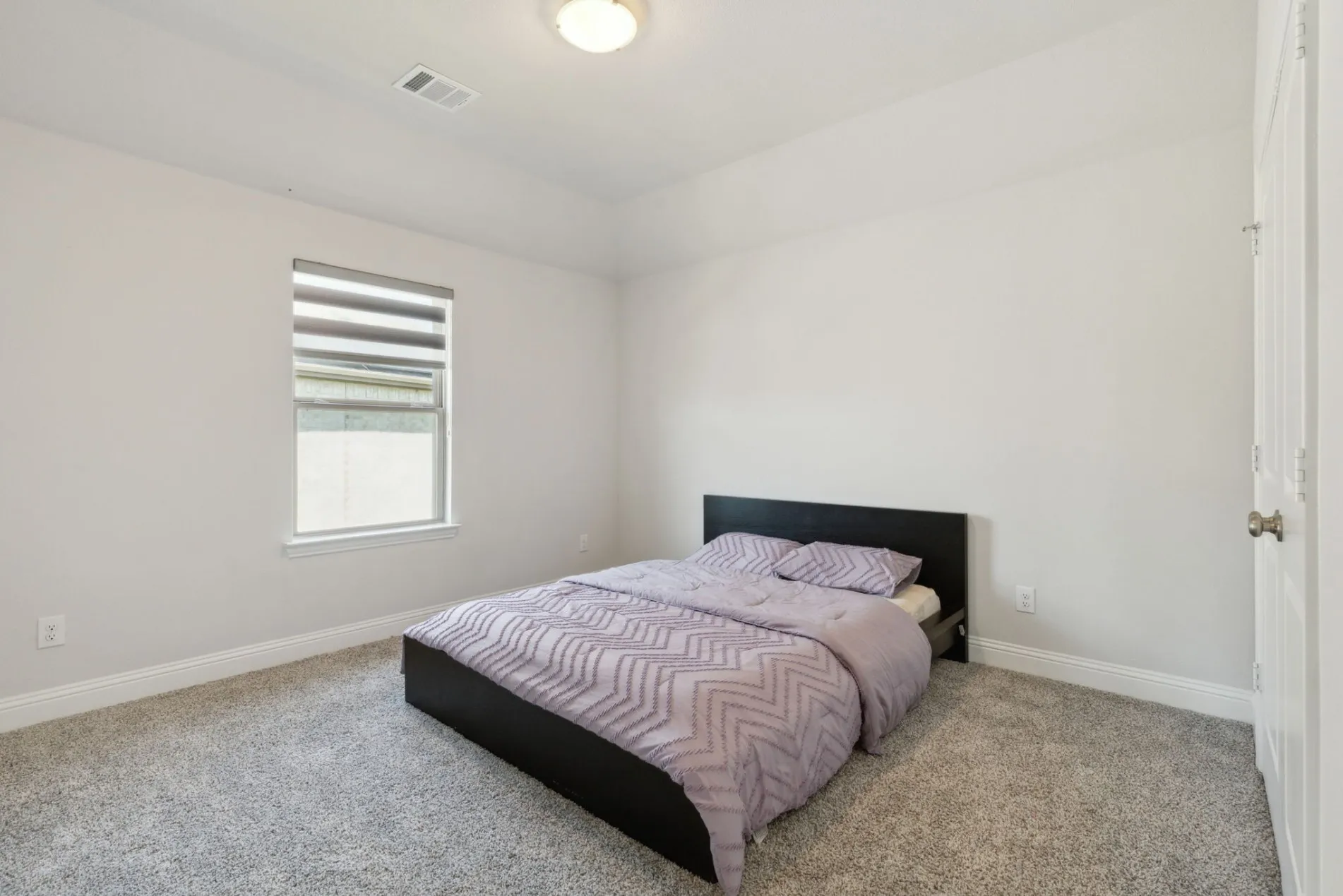 Carpeted room featuring a single window with blinds, a white ceiling fan, and light-colored walls