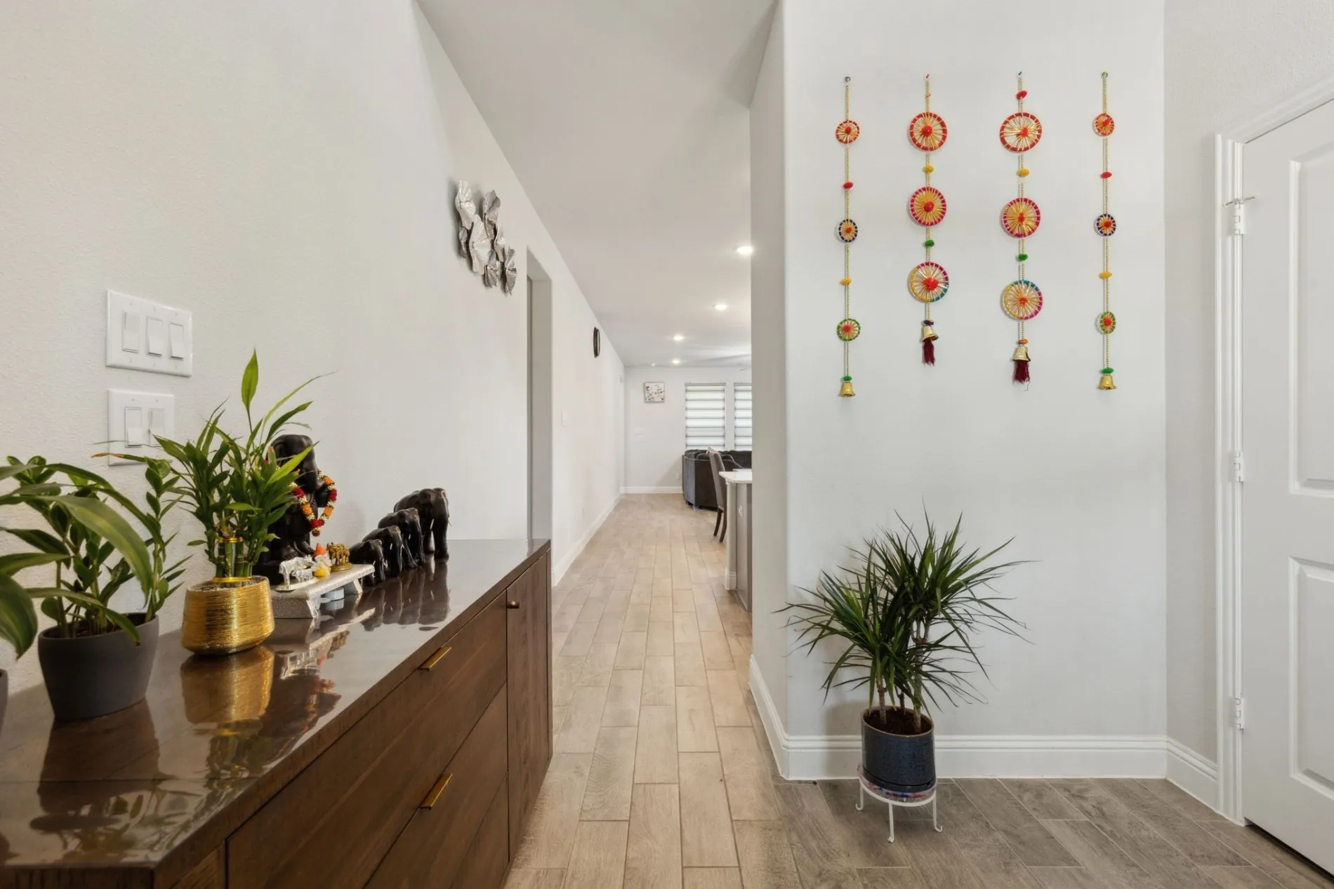 Bright hallway featuring light wood-finish flooring and a built-in wood cabinet with sleek hardware