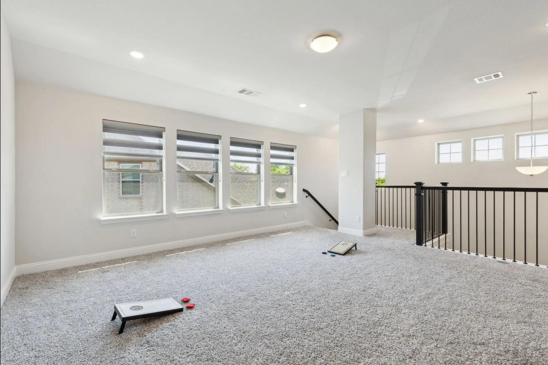 Spacious carpeted room featuring multiple windows with blinds, recessed lighting, and white walls