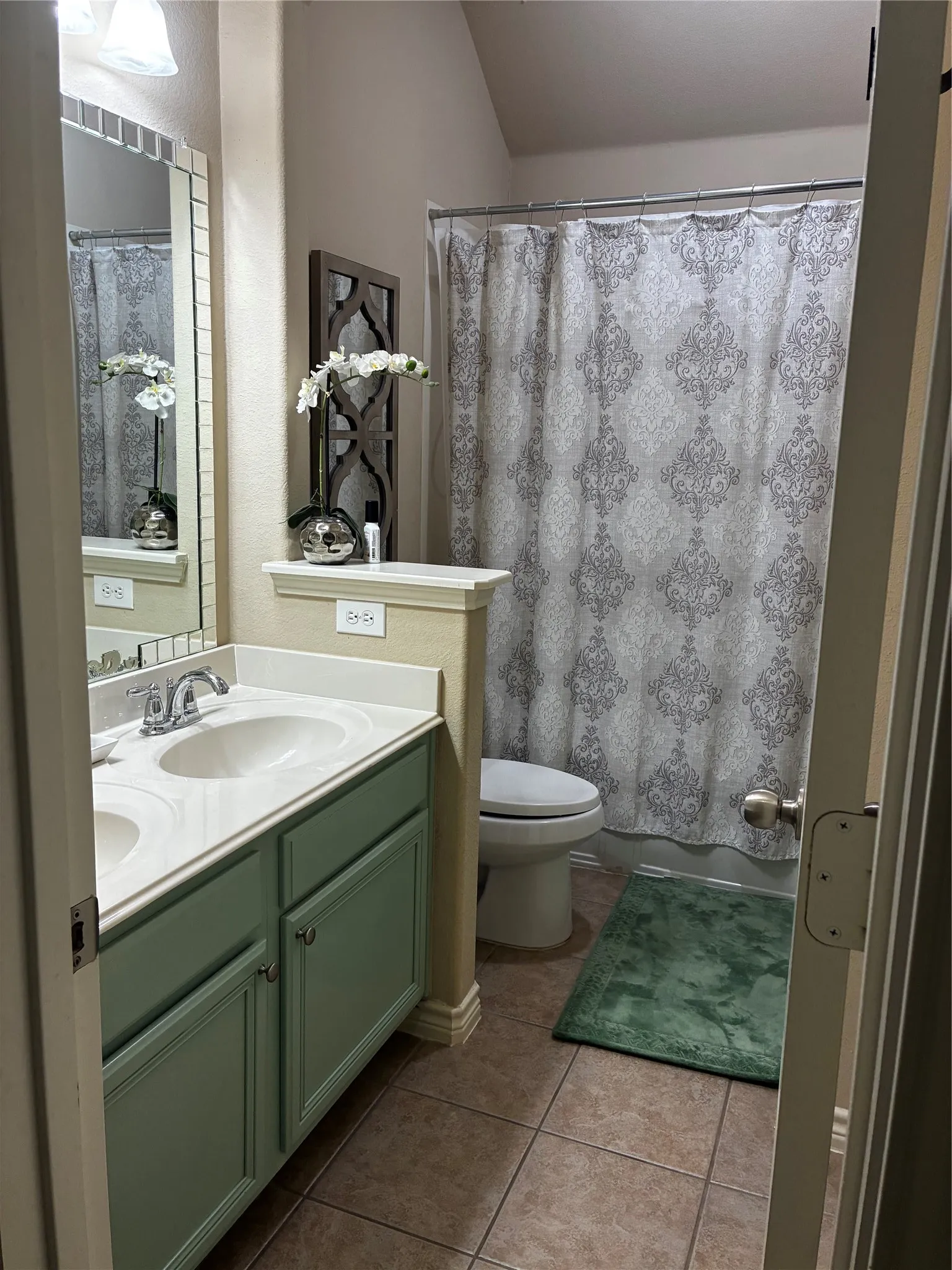 Bathroom featuring a dual vanity with light green cabinetry, white countertops, and integrated sinks