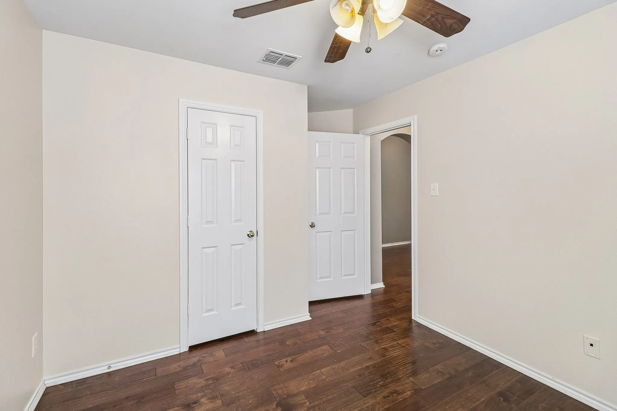 Room featuring dark wood-finish flooring, light-toned walls, and white baseboards