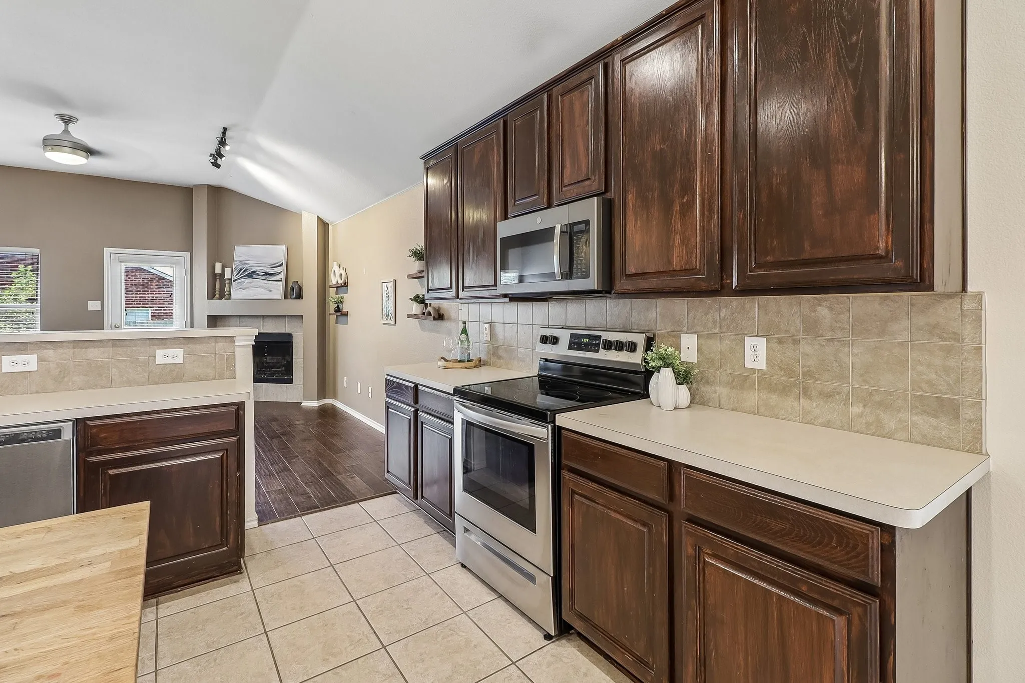 Well-appointed kitchen featuring rich wood cabinetry, light-toned countertops, and a tiled backsplash