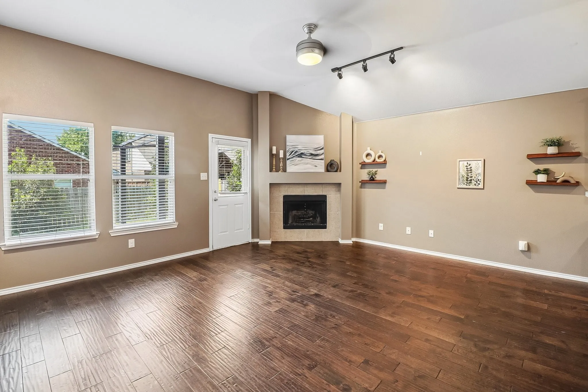 Spacious living area featuring wood-finish flooring, a fireplace with a mantel, and high vaulted ceilings