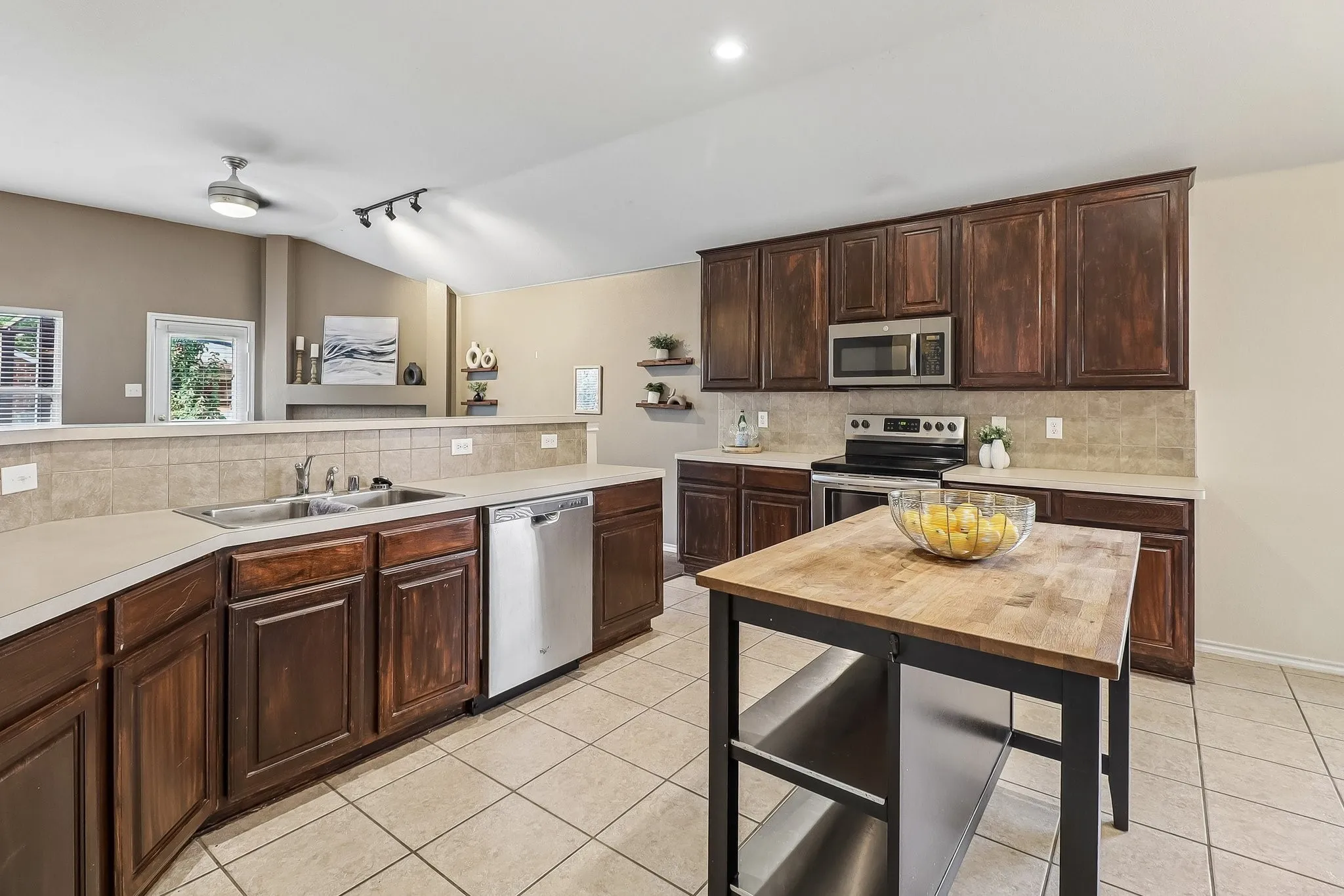 Kitchen featuring dark wood cabinetry, light-toned countertops, and a tiled backsplash