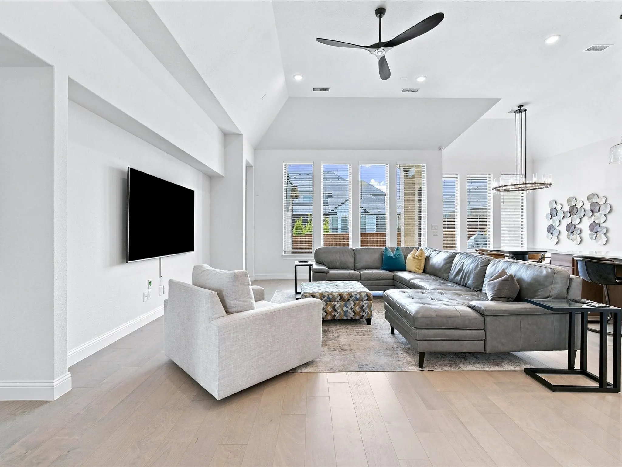 Open-concept living area with light wood-finish flooring, vaulted ceilings, and recessed lighting