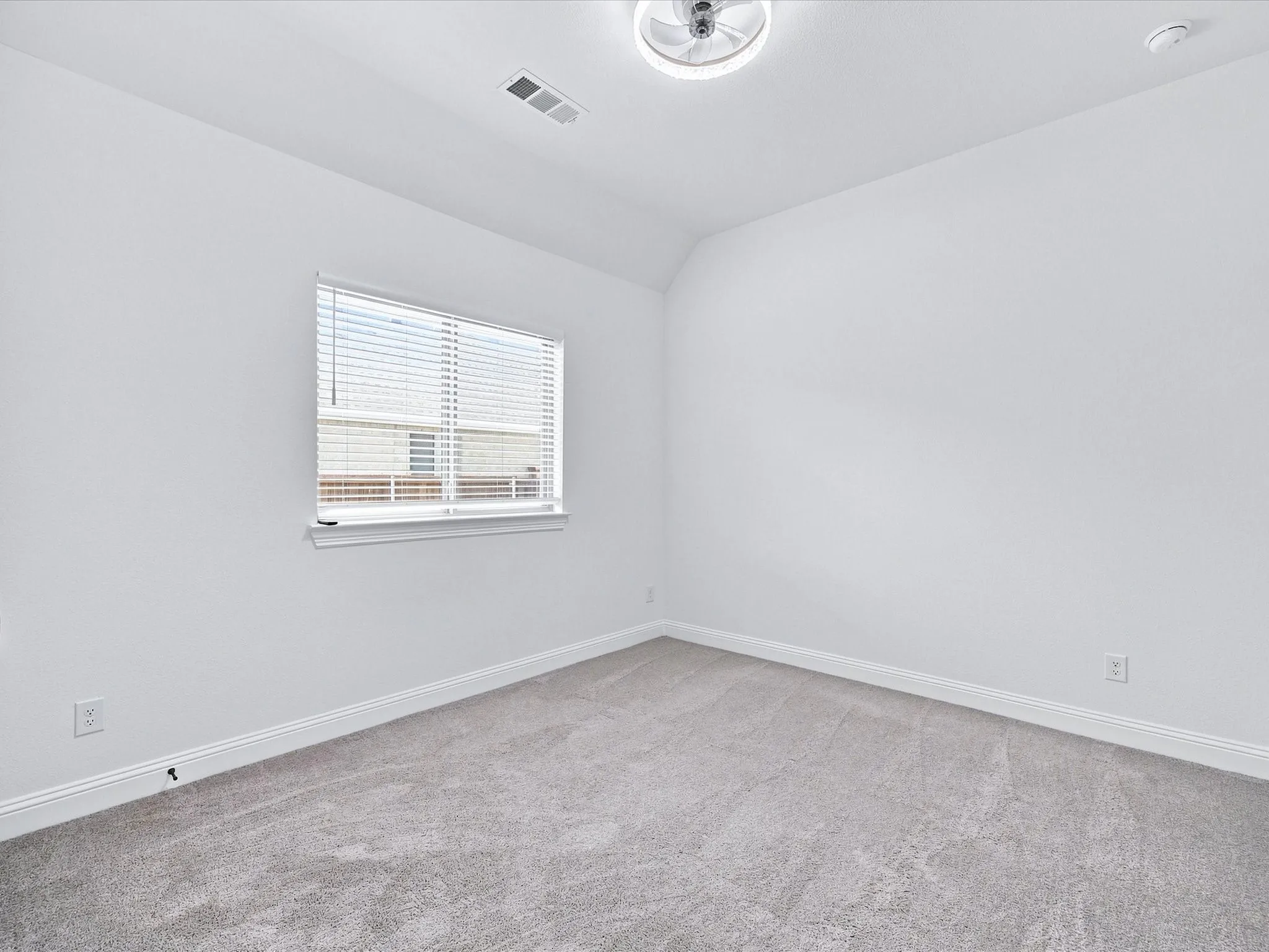 Neutral wall color, carpet flooring, window with blinds, recessed lighting fixture, and angled ceiling detail