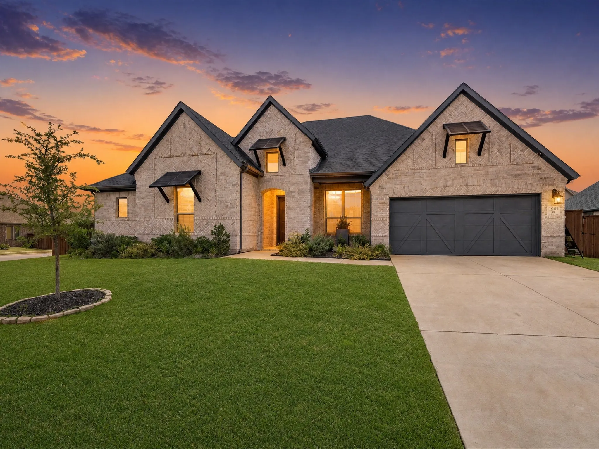 Stone veneer exterior with dark shingle roofing, decorative window awnings, and an arched entry