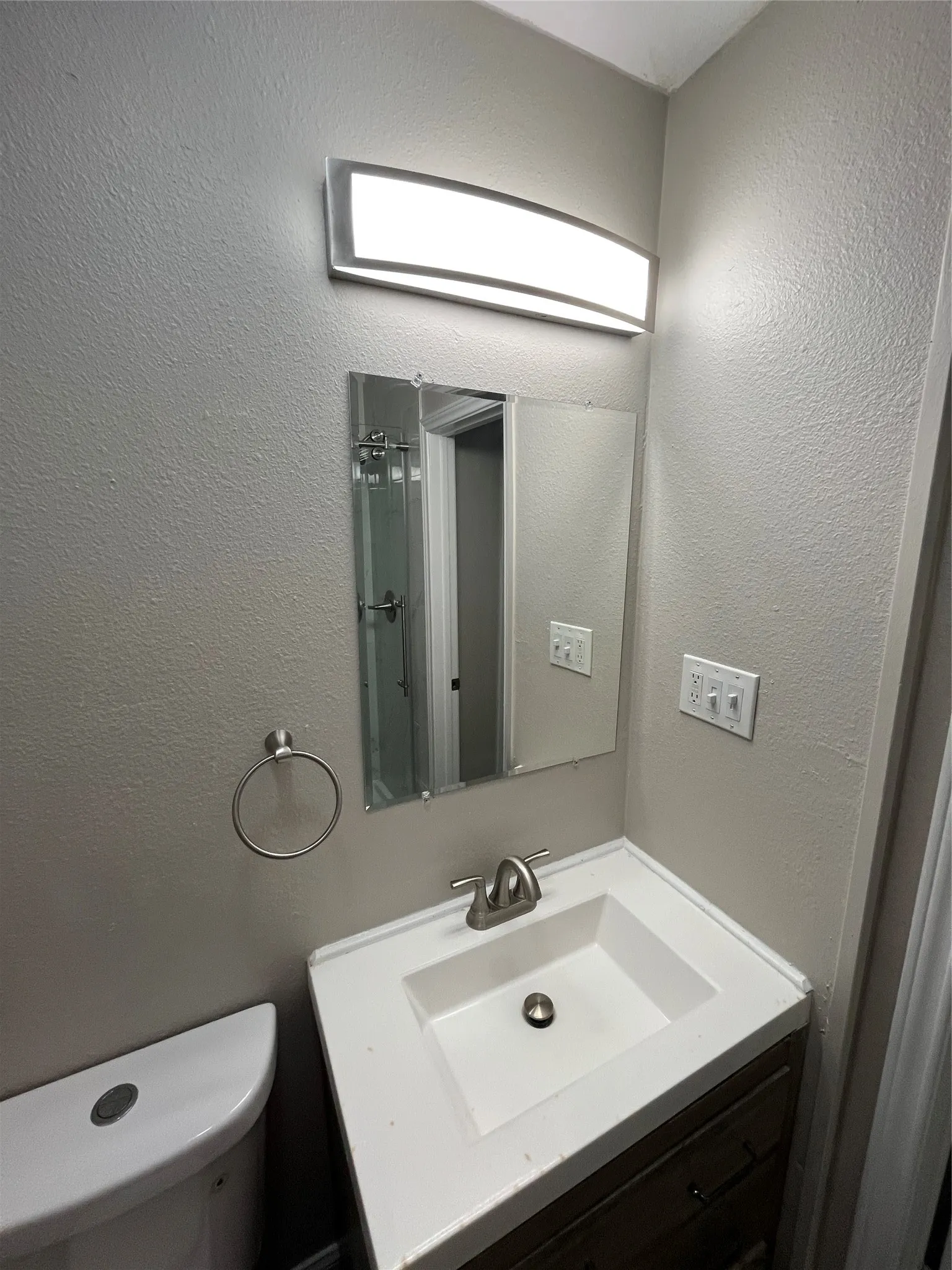 Bathroom vanity featuring an integrated sink, brushed nickel faucet, and a wood-finish cabinet with dark hardware