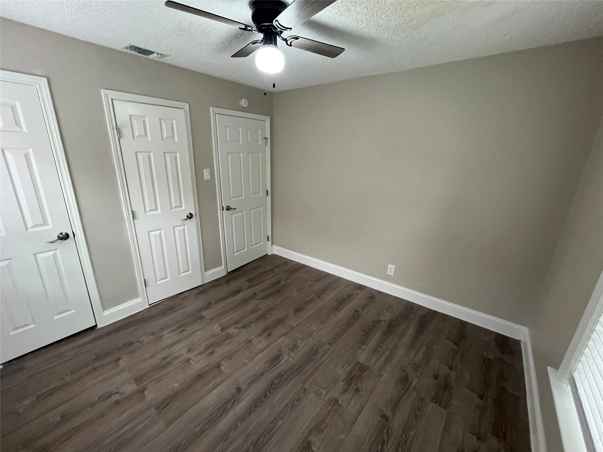 Interior room featuring wood-finish flooring, light neutral wall paint, and white trim