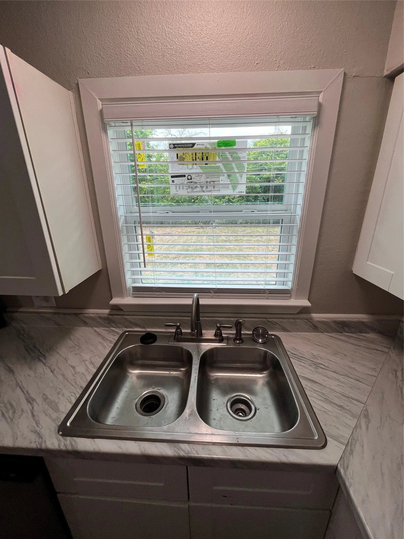 Stainless steel double basin sink with an arched faucet set into a marble-look laminate countertop