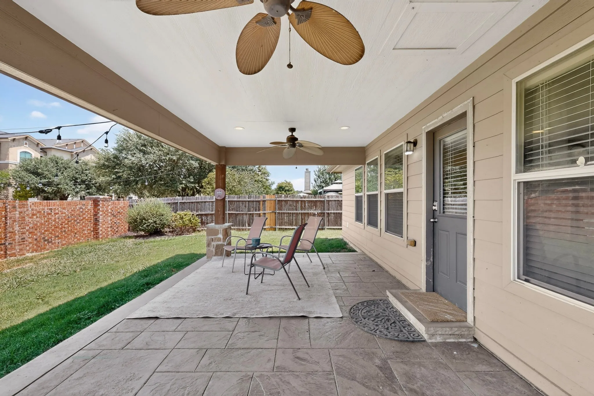 Expansive covered patio featuring stamped concrete flooring, multiple ceiling fans, and integrated lighting