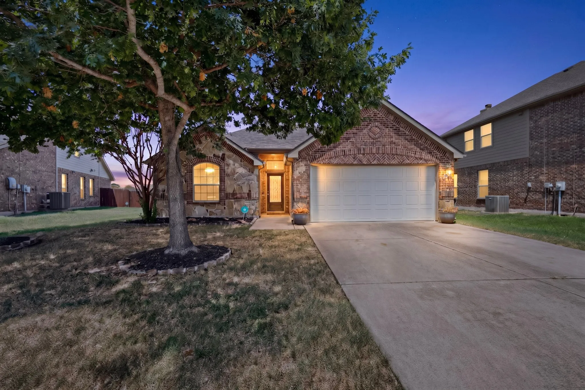 Brick and stone exterior with an arched window, attached garage, and a concrete driveway
