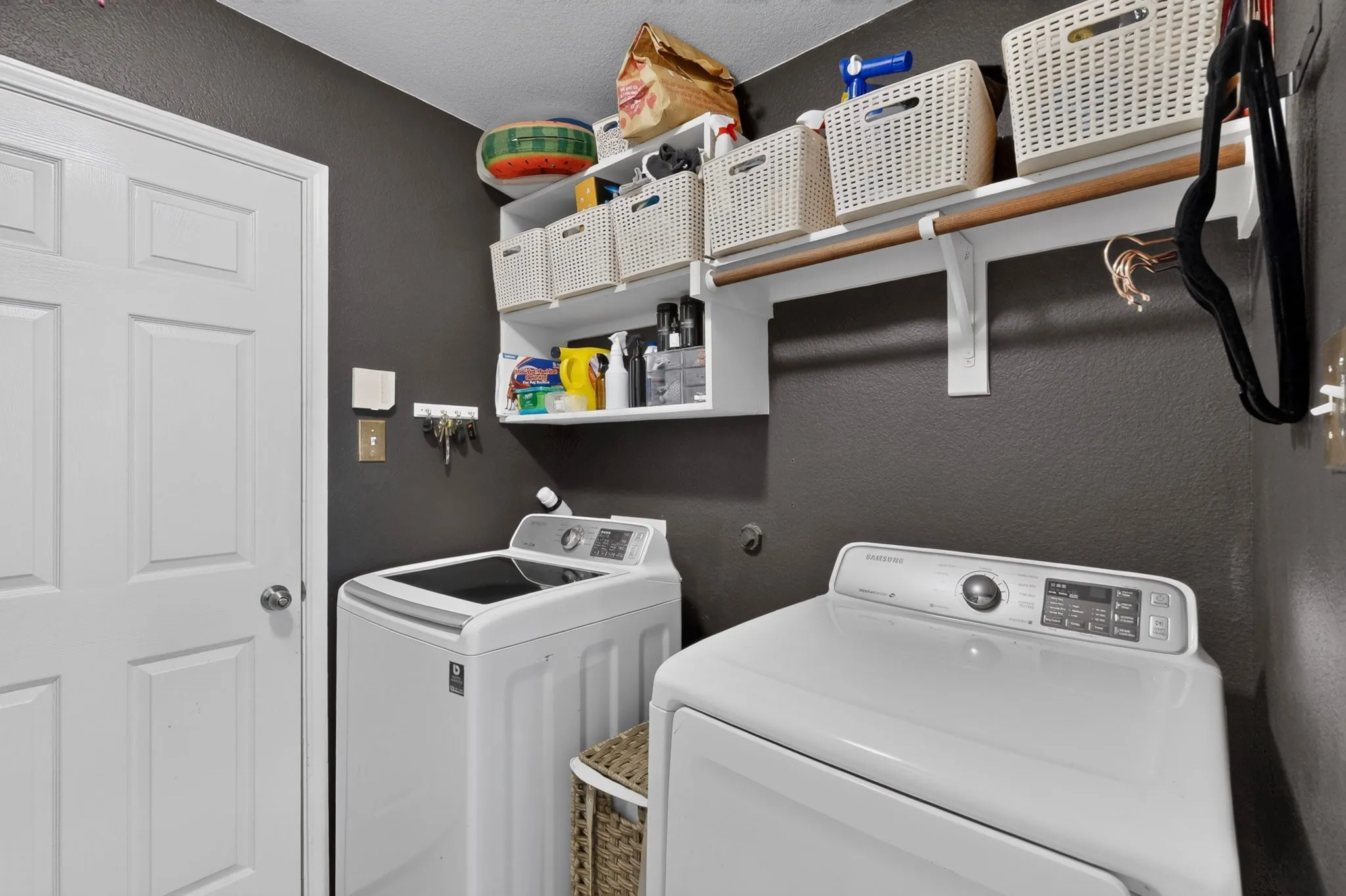 Laundry space featuring a paneled door, built-in shelving, and a hanging rod