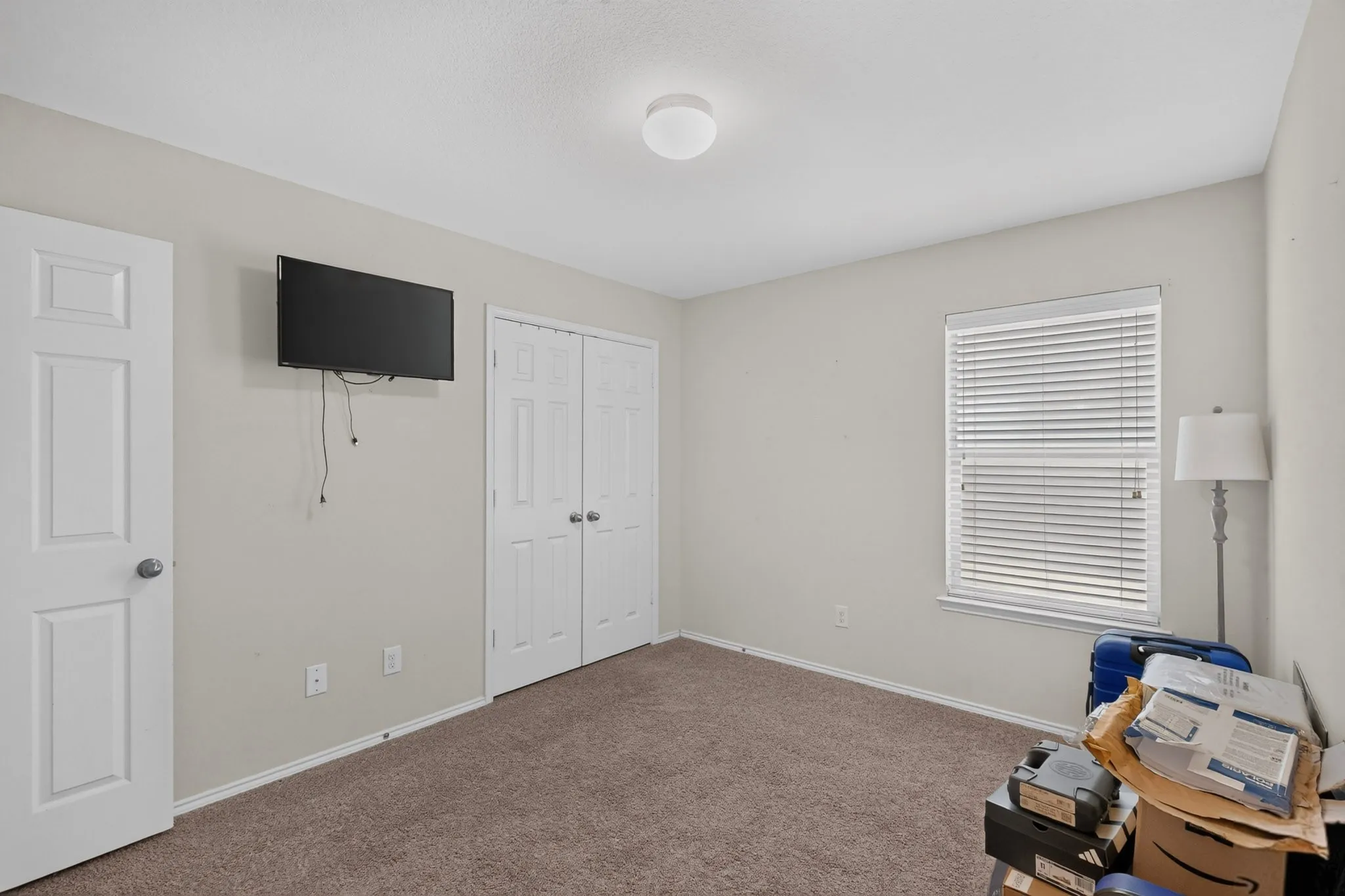 Neutral paint palette, carpeted flooring, window with blinds, bi-fold closet doors, and flush-mount ceiling light