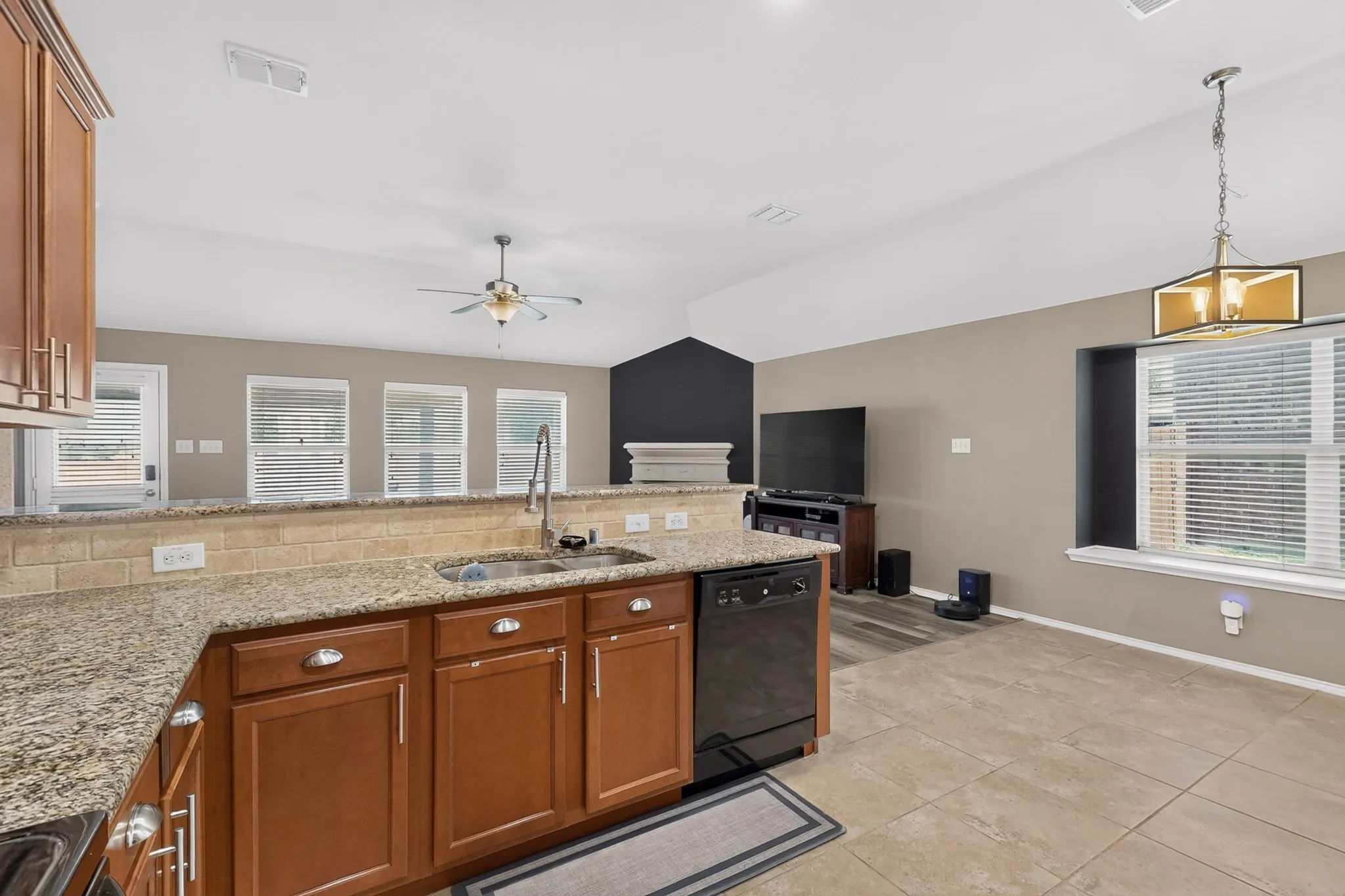 Kitchen featuring ample wood cabinetry, a built-in dishwasher, granite countertops, and a tile backsplash