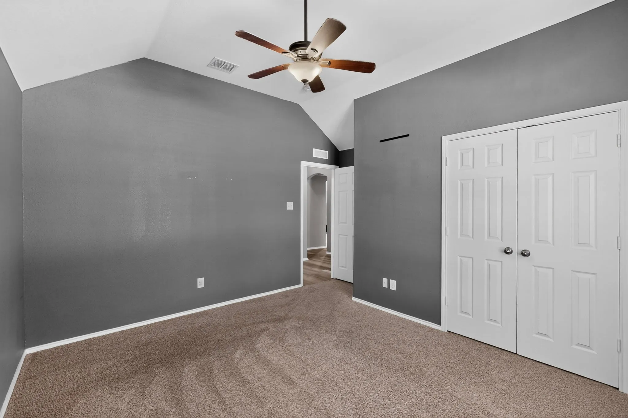 Vaulted ceiling with an attached ceiling fan, neutral carpet flooring, and white paneled doors