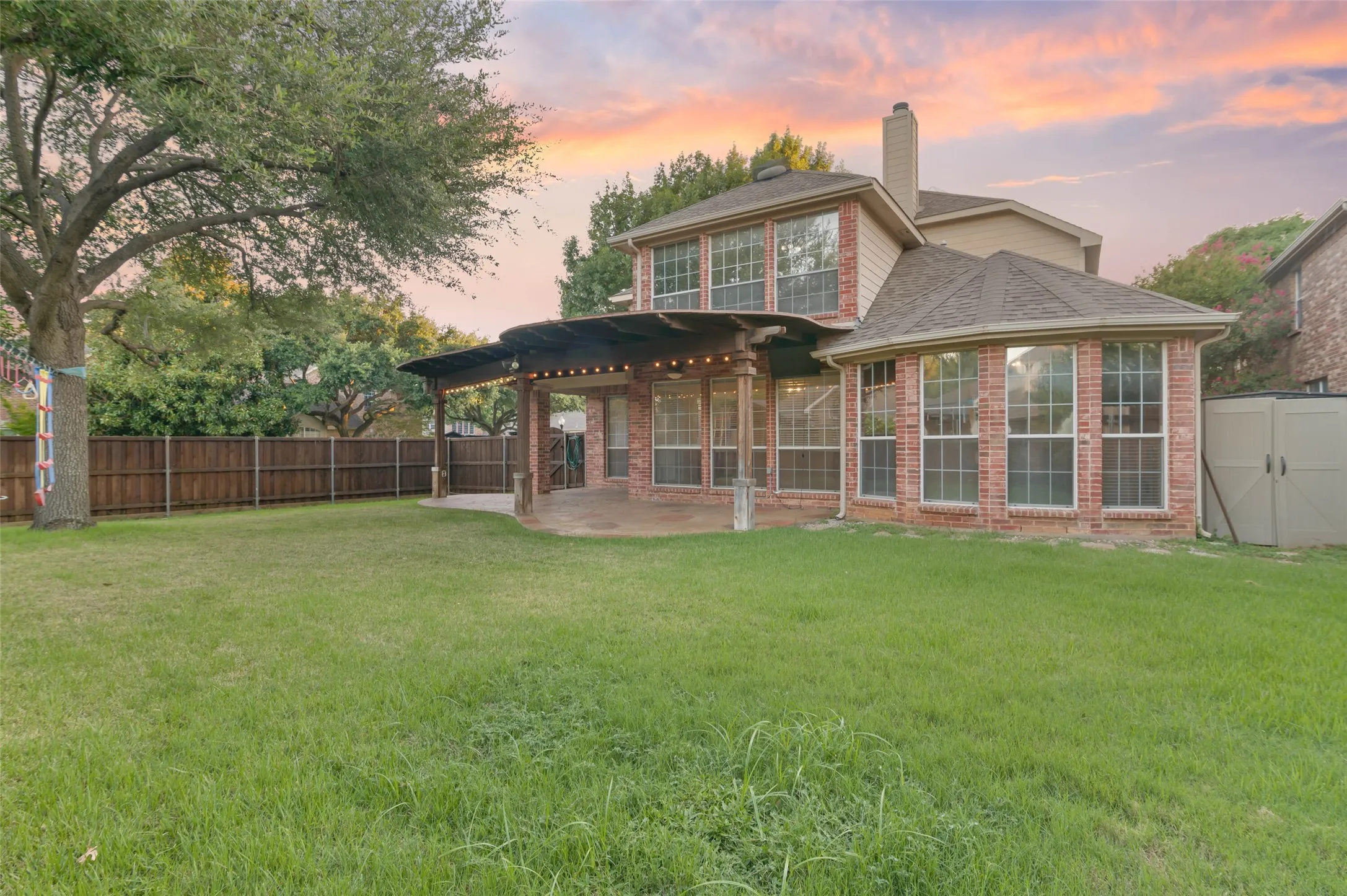 Large back yard with covered patio and shade trees.