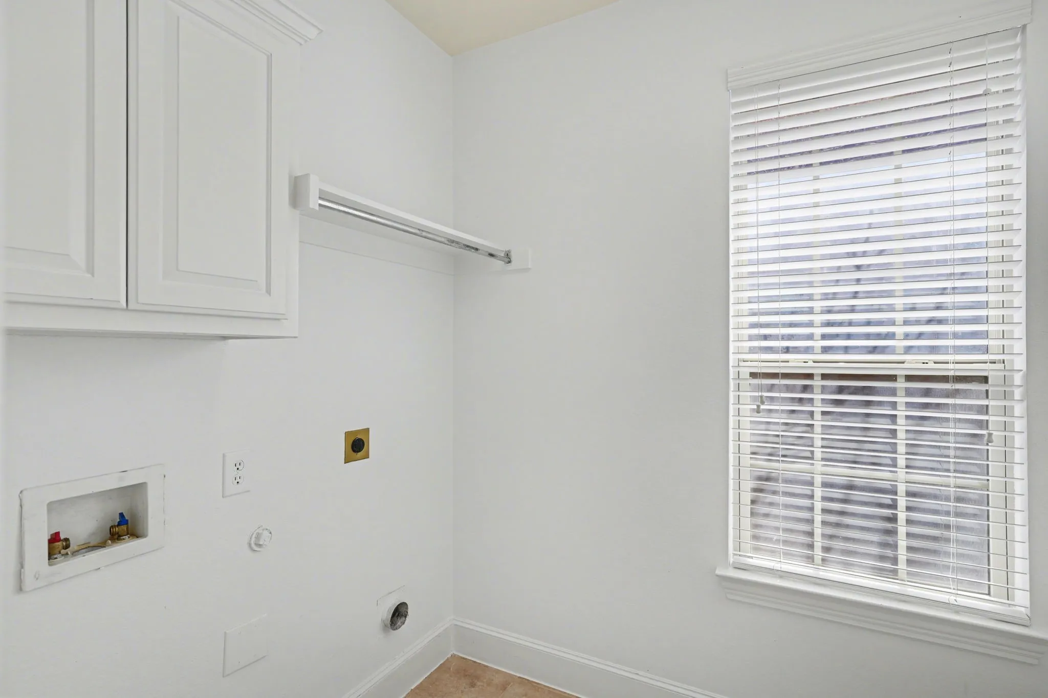 Dedicated laundry area featuring white cabinetry and a window with blinds