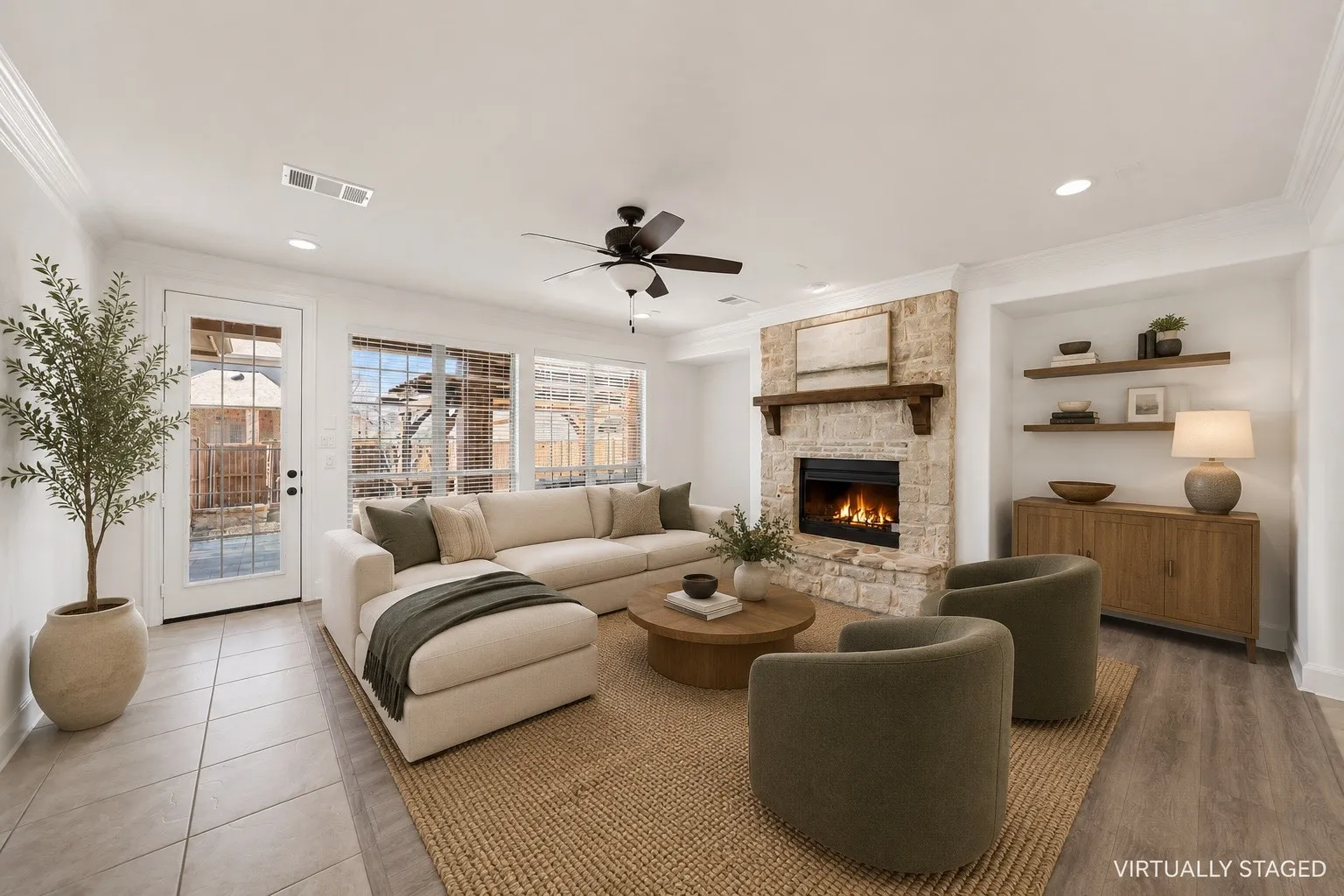 Spacious living area featuring a stone fireplace with wood mantel, a ceiling fan, and multiple windows