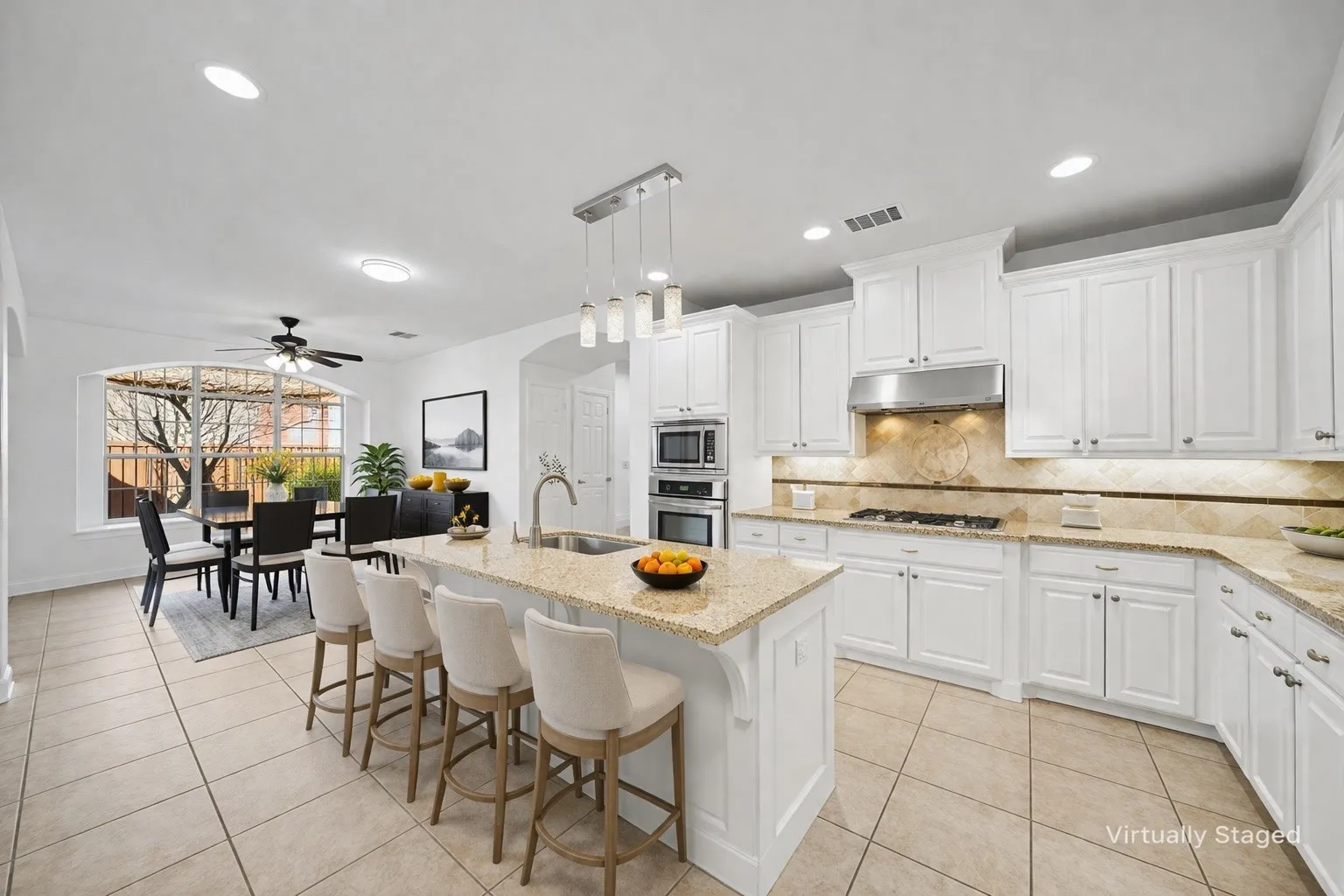 Expansive kitchen featuring white cabinetry, a stone-finish countertop, and a built-in stainless steel range hood