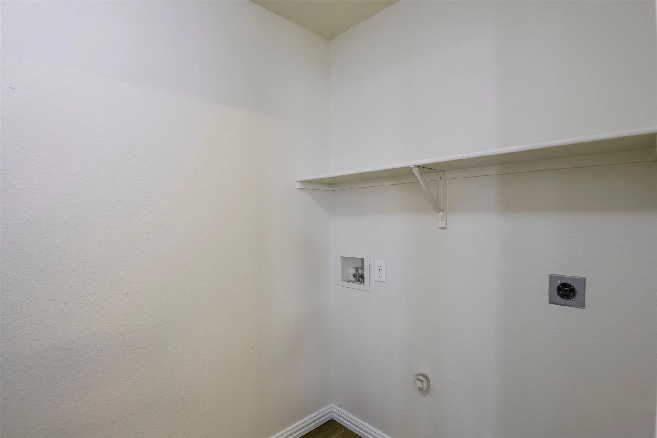 Dedicated utility space featuring washer/dryer hookups and a built-in storage shelf